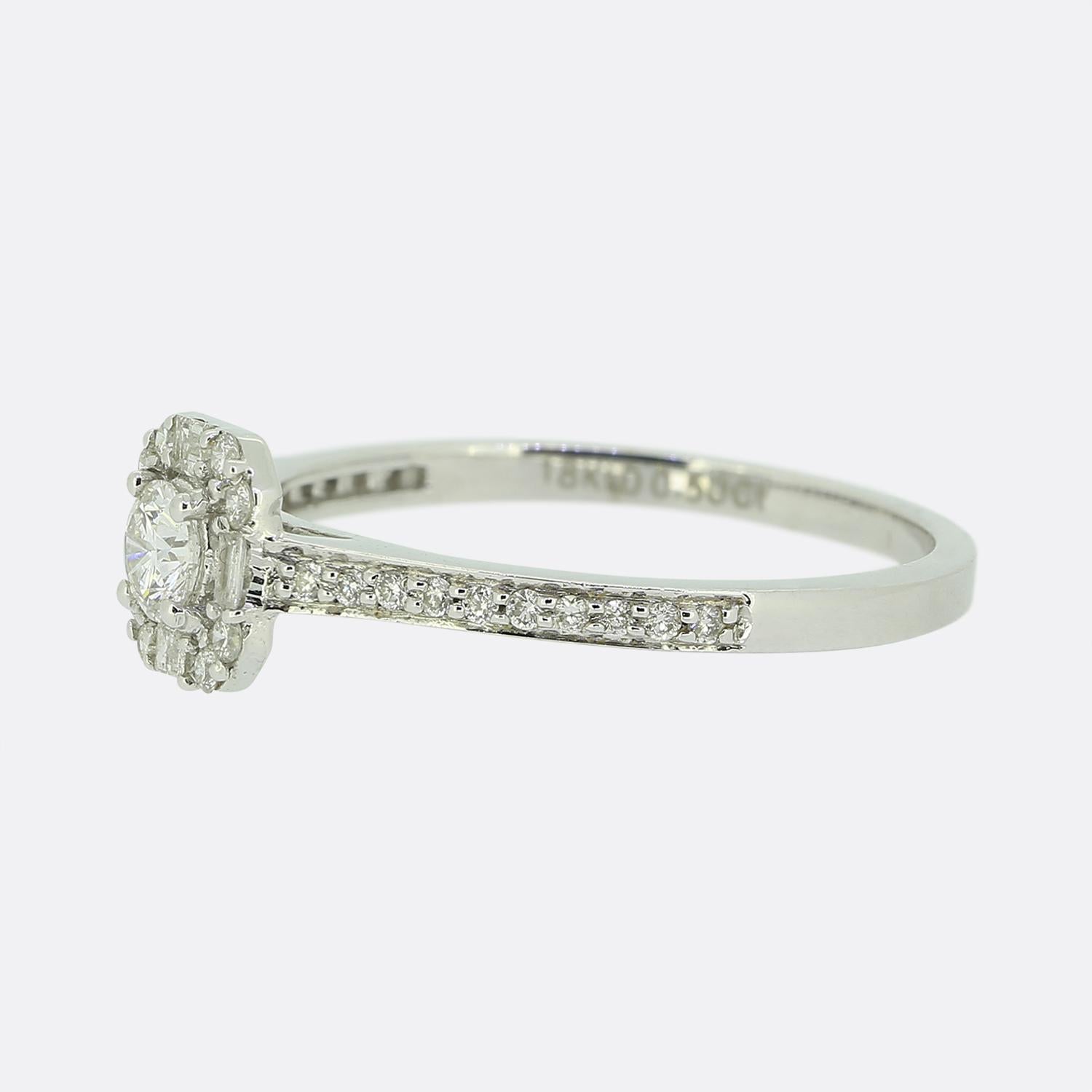 Questo è un anello con diamante in oro bianco 18ct. Il punto focale dell'anello è un diamante rotondo taglio brillante da 0,15 carati, contornato da 4 diamanti taglio baguette e 8 diamanti rotondi più piccoli. Su ogni spalla sono incastonati 10
