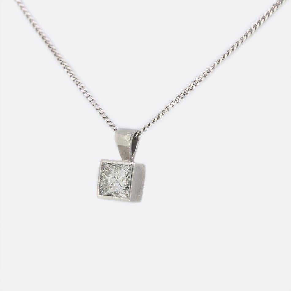 This is a single stone diamond pendant necklace. The pendant features a single princess cut diamond that has been rubover set in 18ct white gold and suspended on an 18ct white gold chain.

Condition: Used (Very Good)
Weight: 1.9 grams
Length: 16