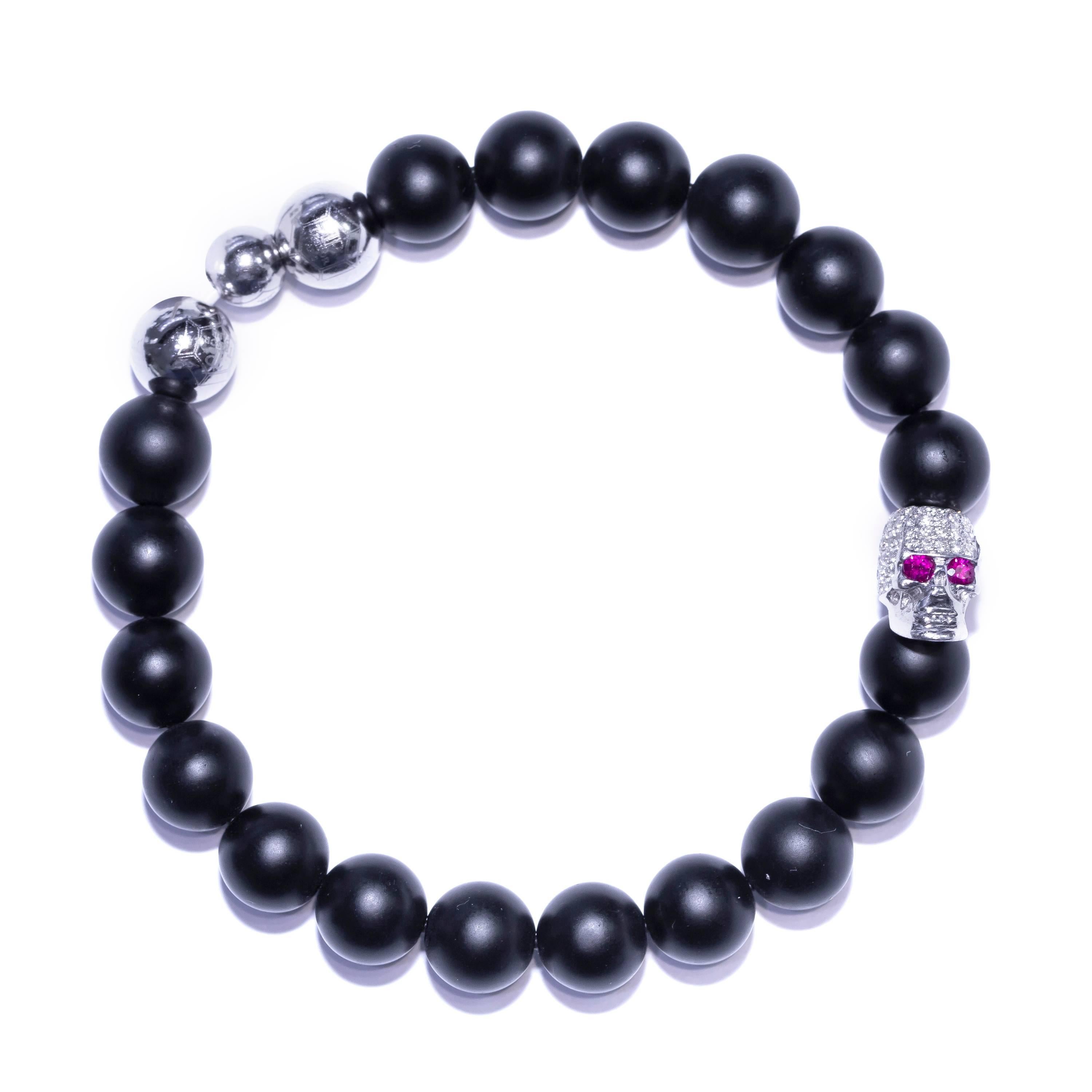 The Original Tresor Paris Bracelet from the Vega collection having one Pave set Diamond skull 0.50 Carat round diamond set in 18 Karat White Gold and Ruby eyes, 3 stainless steel beads and 19 matte black satin agate beads 8mm. Size will fit from