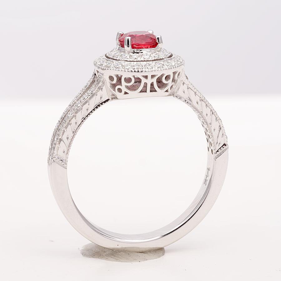 This exquisite ring showcases a deep and fiery red spinel, known for its intense color. The elegant design features two halos of pave-set diamonds that extend onto the ring's shoulders, adding extra sparkle and brilliance. Handcrafted in 14K white