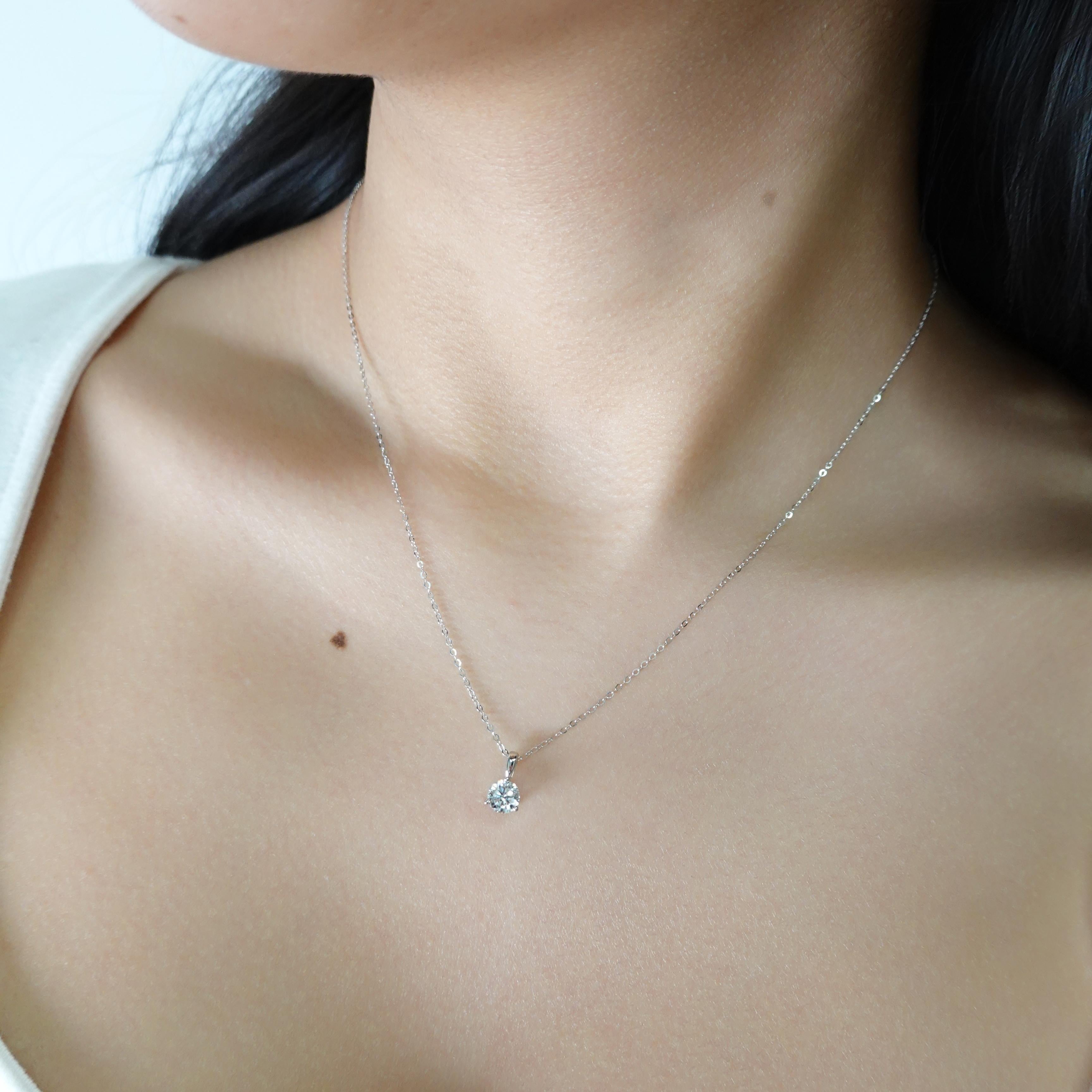 Le collier solitaire en or 14 carats est orné d'un diamant naturel de taille ronde de 0,50 carat, serti sur une monture à griffes. Le diamant a une pureté de SI1 et une couleur de FG. Le collier est accompagné d'un câble réglable de 1 mm de long. Il