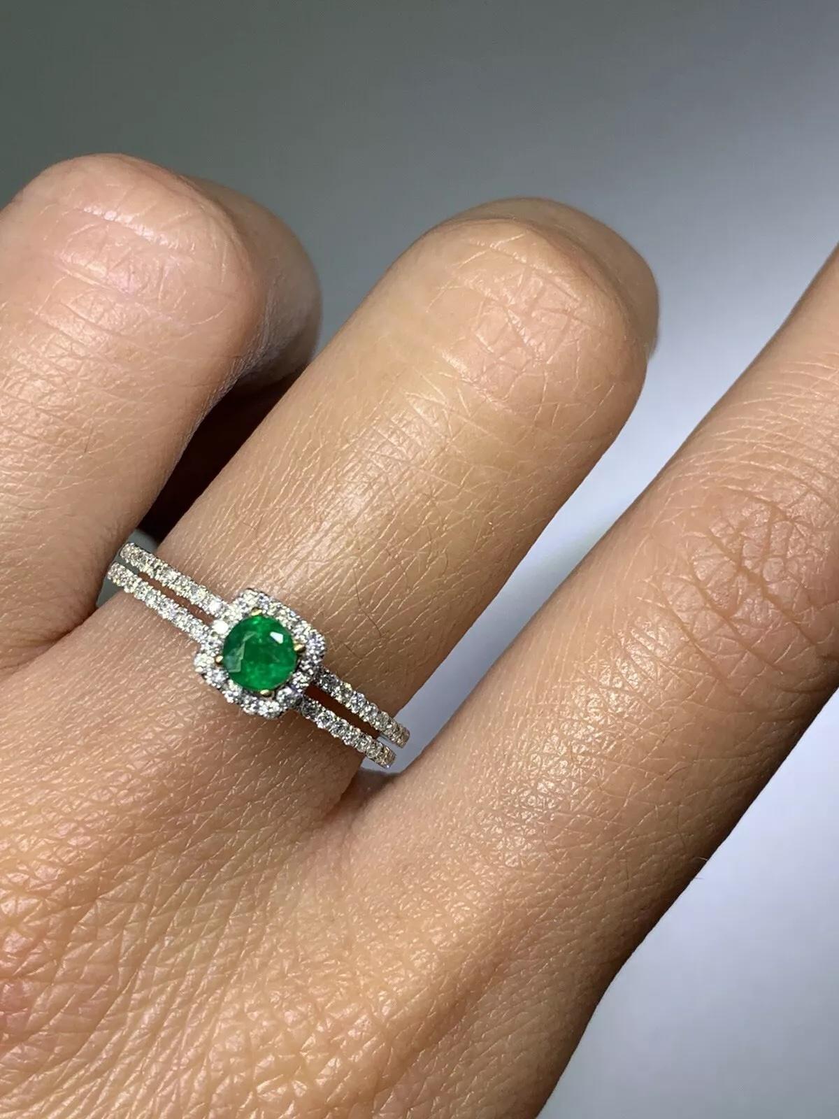 Cette bague exquise présente une magnifique émeraude colombienne naturelle de 0,50ct entourée d'un halo de diamants étincelants. L'émeraude a une riche couleur verte, tandis que les diamants ont une couleur F et une pureté VS1. La bague est
