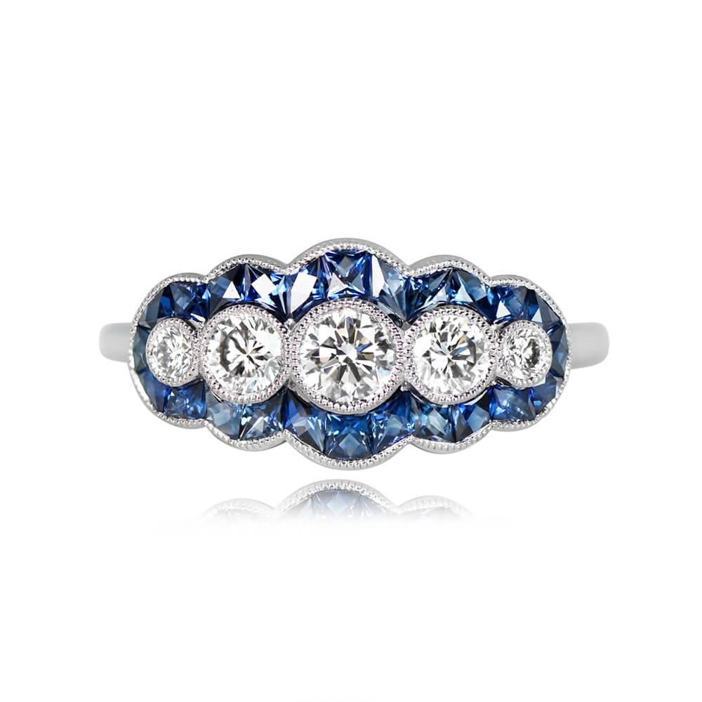A stunning diamond and sapphire halo ring with five east-west bezel-set round brilliant cut diamonds, totaling approximately 0.50 carats (I color, VS1 clarity). It's surrounded by a halo of French-cut natural sapphires weighing 0.75 carats in total.