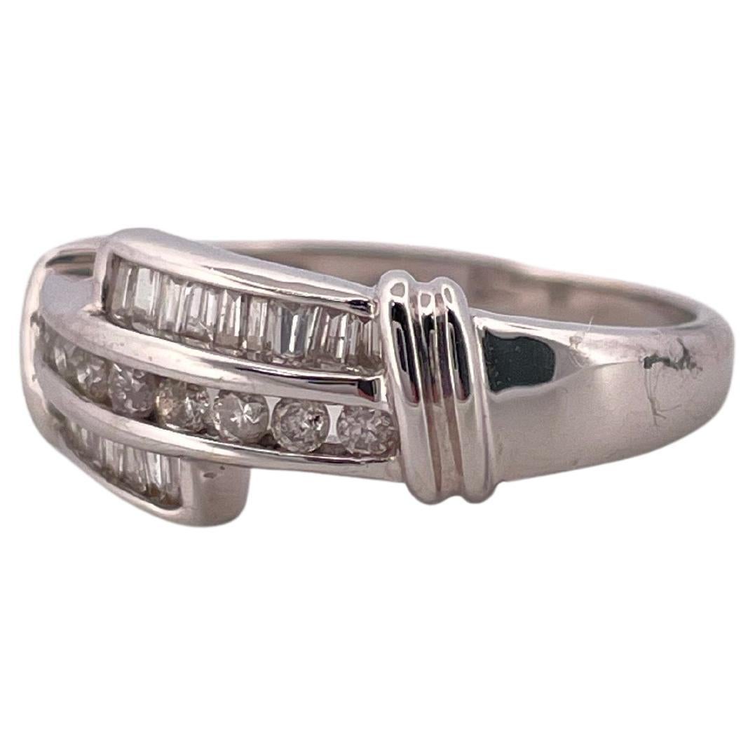 Dieses elegante Diamantband aus 14 Karat Weißgold bietet eine raffinierte Mischung aus Brillanz und Raffinesse. Das Design zeichnet sich durch eine auffällige Anordnung von runden Brillanten und Diamanten im Baguetteschliff aus, die in einem