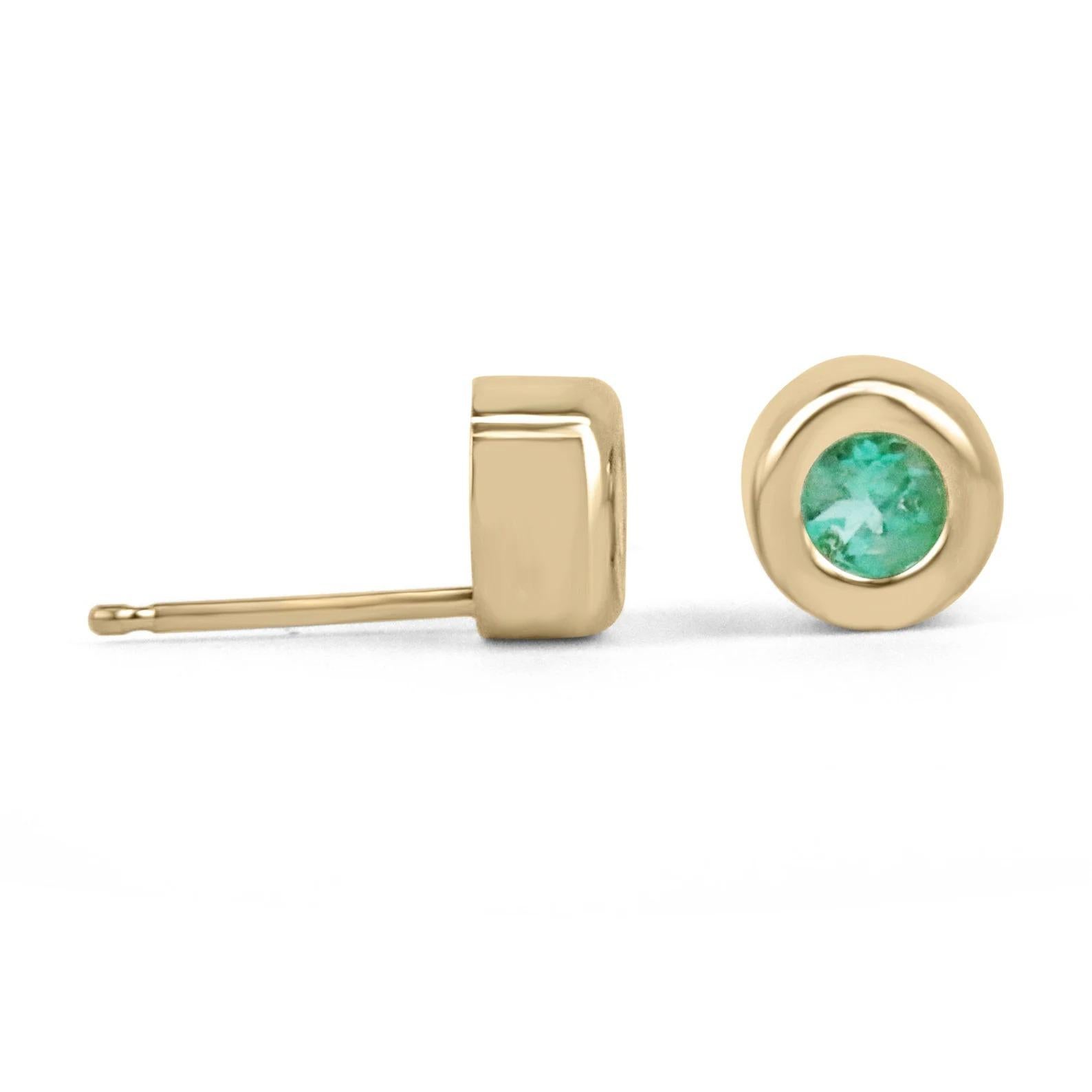 A stunning and simple pair of emerald stud earrings. This delicate and dainty pair, showcase two petite round cut Colombian emeralds weighing a total of half a carat. The gemstones display a beautiful light spring green color, and amazing