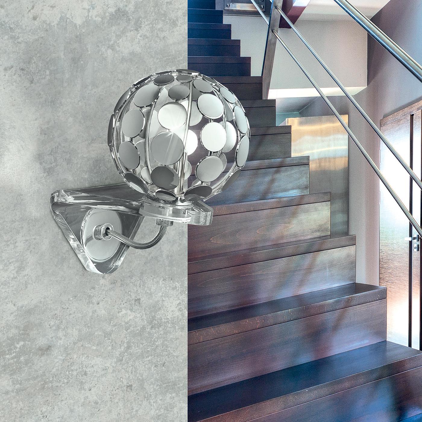 Inject a glamorous touch into any living space with the disco ball wall light. Its spherical diffuser is formed of individual chrome discs, projecting a dazzling interplay of light effects onto the walls. Finished with a transparent triangular base