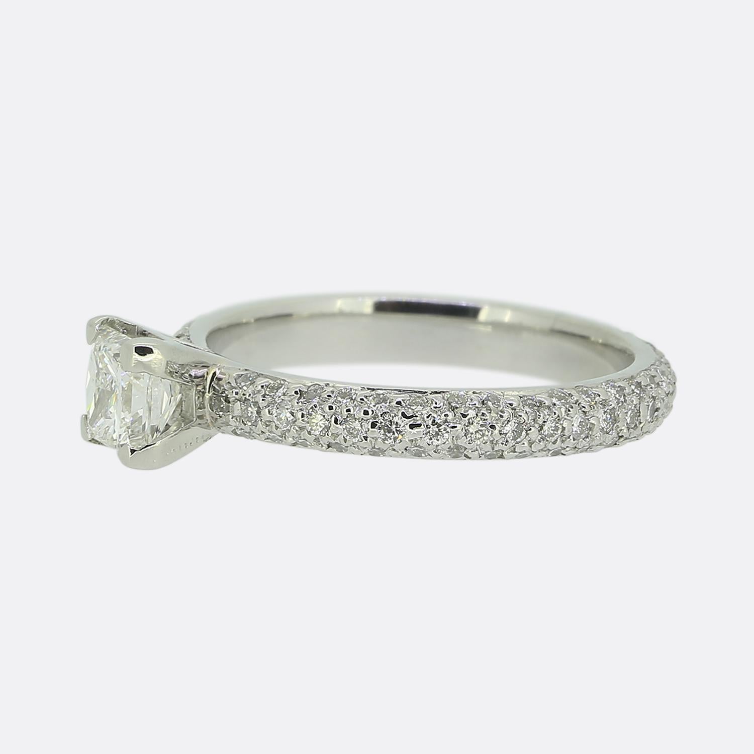 Here we have a gorgeous diamond engagement ring. At the centre of the face we find a stunning bright white 0.52 carat princess cut diamond set in a 4 clawed mount. This principal stone sits alone and proud atop a platinum band set with over 100