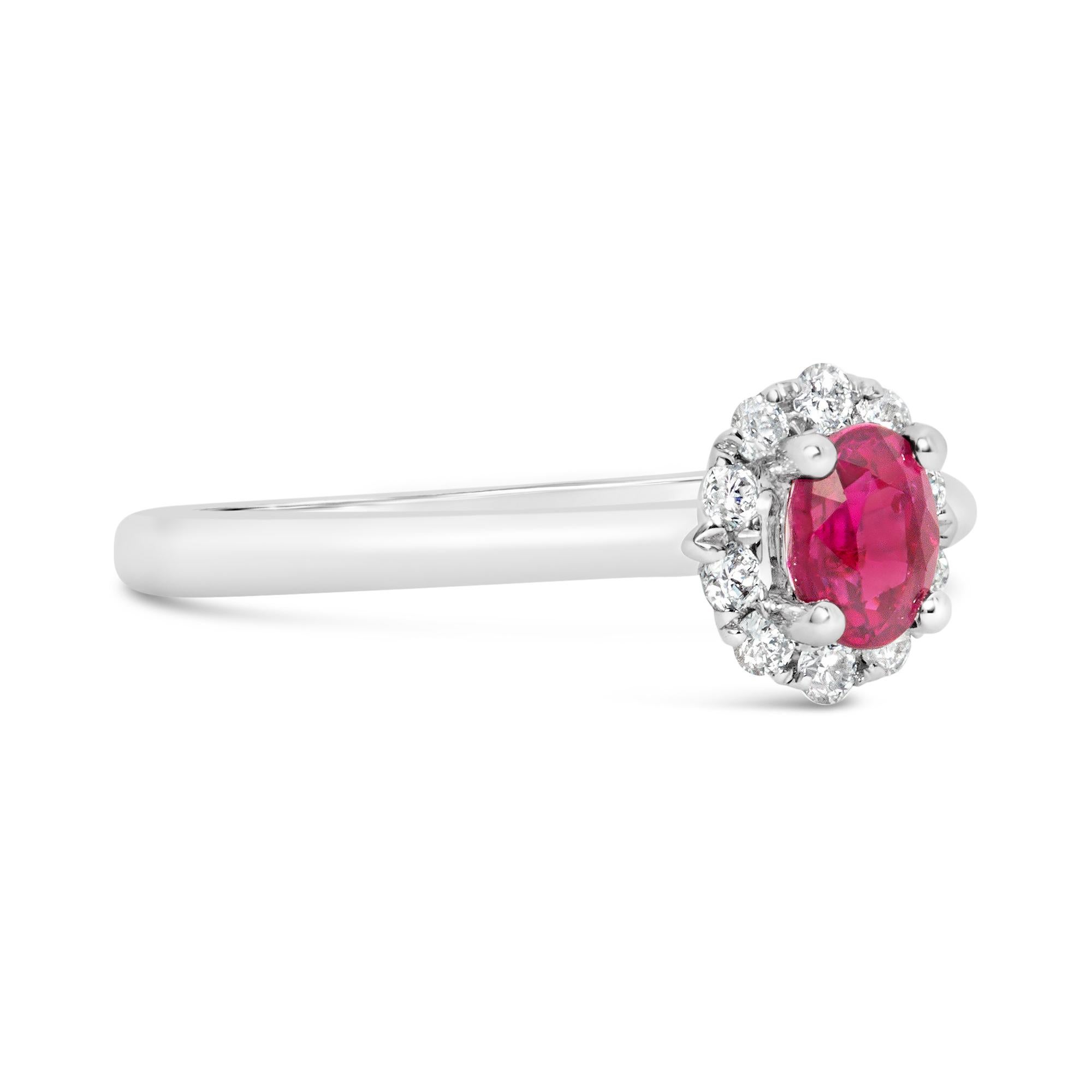 A classy engagement ring, featuring a 0.53 carat oval cut ruby, set on a classic four prong setting. Accented by a halo of 10 round brilliant cut diamonds weighing 0.16 carat total. Finely made with an 18K white gold mounting. Size 6.5 US, resizable
