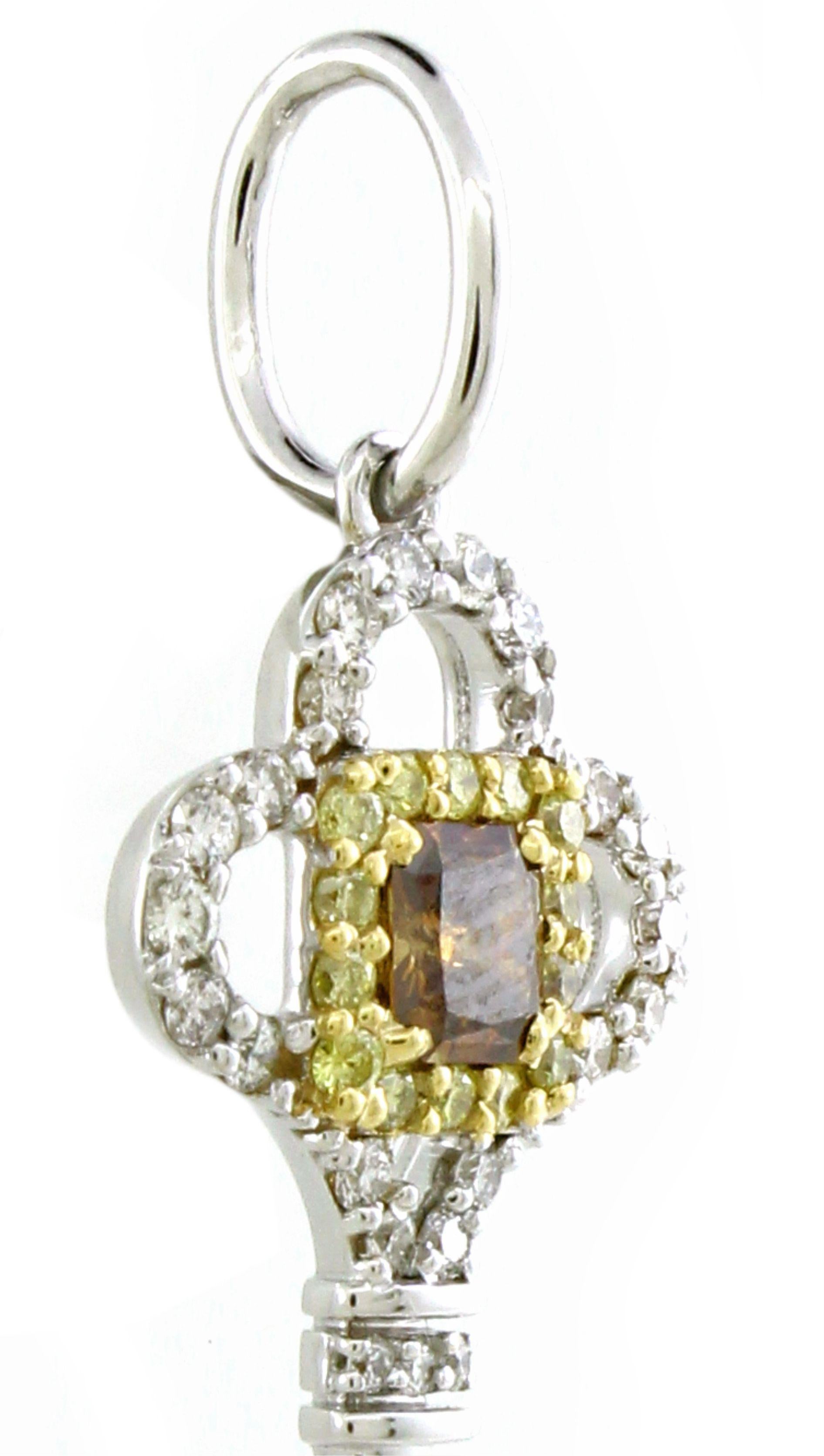 Questo sofisticato ciondolo unisex presenta un'impressionante silhouette a forma di chiave, realizzata in lussuoso oro bianco 18 carati e dal peso di 2,15 grammi. Al centro, un affascinante diamante marrone taglio princess di 0,19 carati è