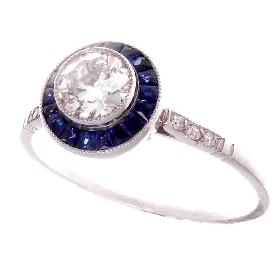 A stylish recreation from the art deco era. Featuring a lively 0.54 carat round brilliant cut diamond surrounded by a halo of vibrant blue sapphires. A colorful and well made ring, lovingly hand crafted in platinum. 

Ring size 7 and may easily be