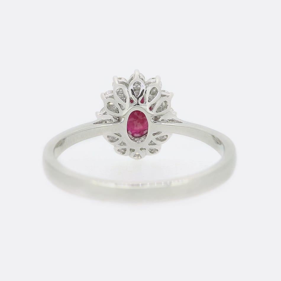Anillo de oro blanco de 18 ct con rubíes y diamantes. Presenta un único rubí de talla oval rodeado por un racimo de 12 diamantes de talla brillante engastados en una garra de oro blanco.

Estado: Usado (Excelente)
Peso: 2.7 gramos
Tamaño del anillo: