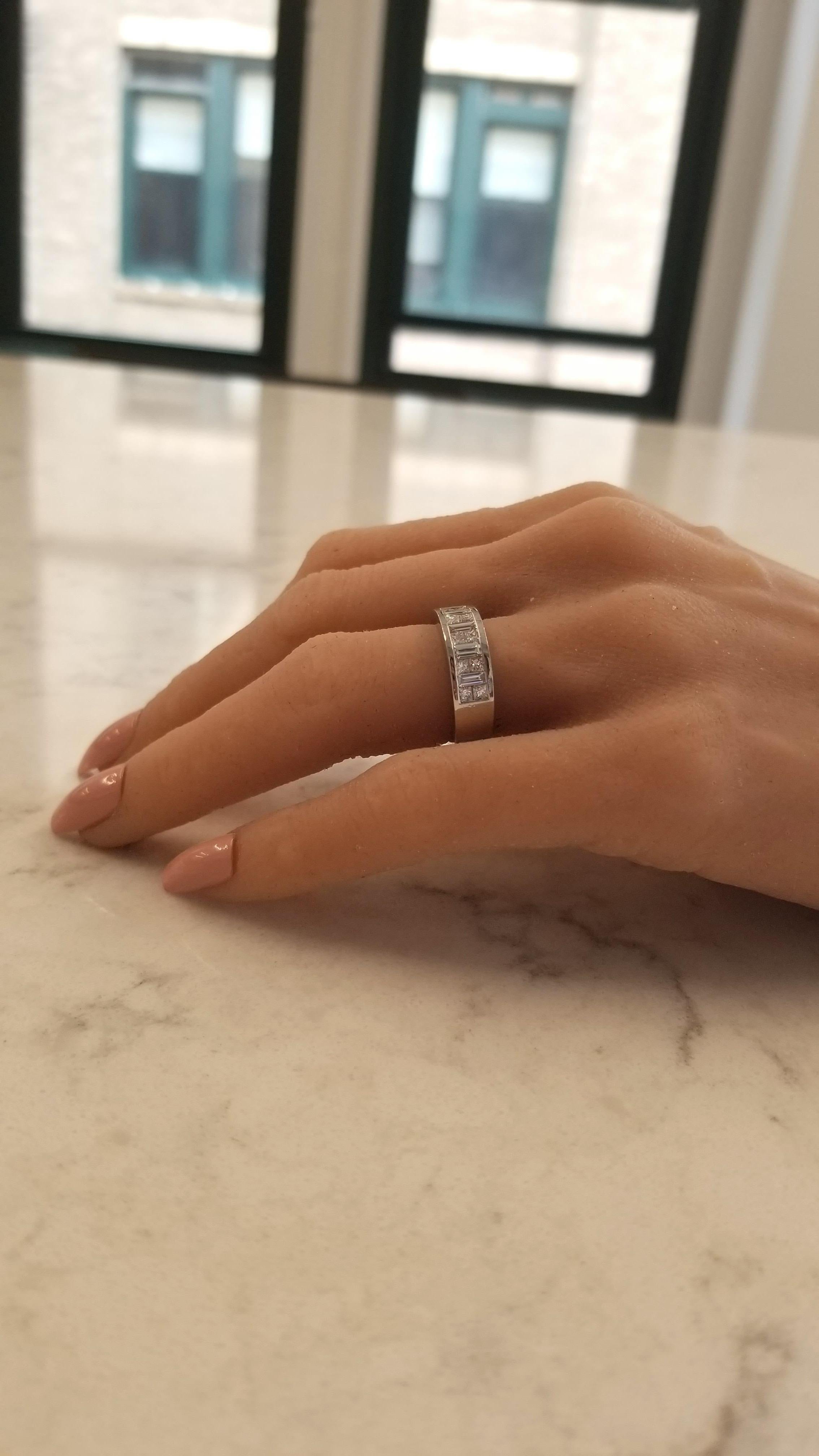 Ideal as a dream wedding or anniversary band, this gorgeous brightly polished platinum diamond band features a total of 0.55 carats of invisibly channel set diamonds, along with 0.52 carats of princess cut diamonds that alternate on the top in a