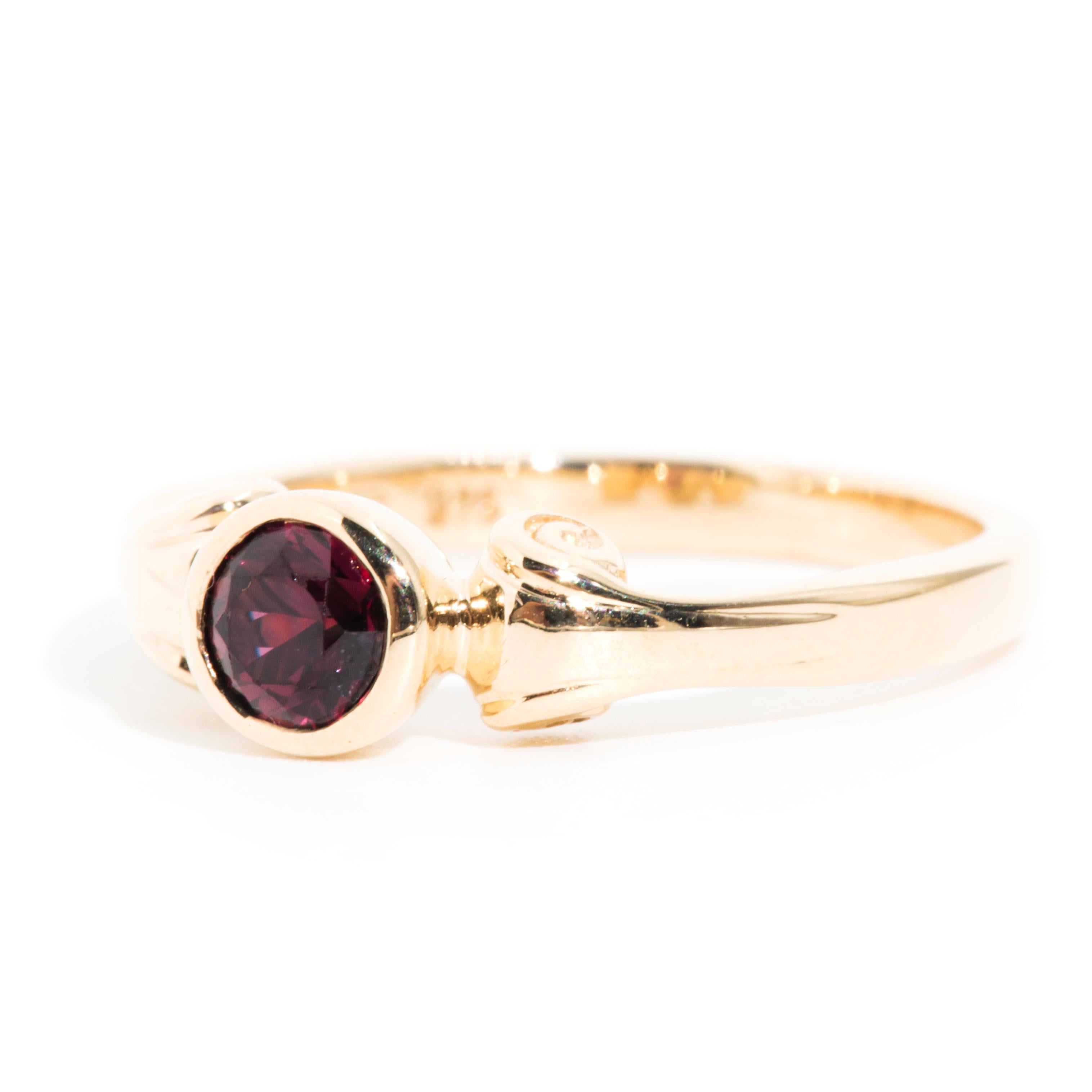 Crafted in 9 carat yellow gold, this lovely vintage adornment features a gorgeous deep red ruby encased in a bezel setting atop a nostalgic scrolled gold band. We have named this charming vintage solitaire ring The Aaliyah Ring.  The Aaliyah Ring