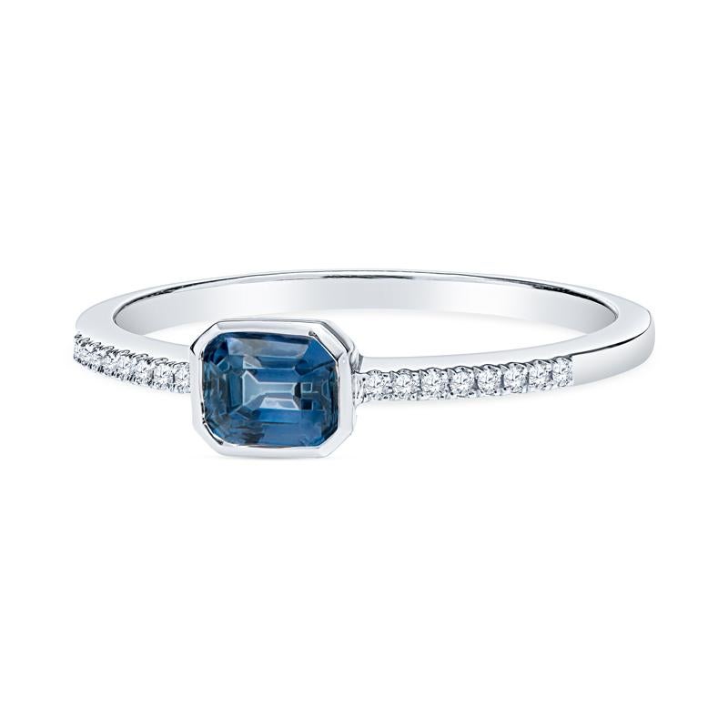 This petite and dainty ring features a 0.56 carat emerald cut blue sapphire set in 14 karat white gold and accented by diamonds on the band. It is a size 6.5 but can be resized upon request. Wear alone or stack with your other favorite rings.