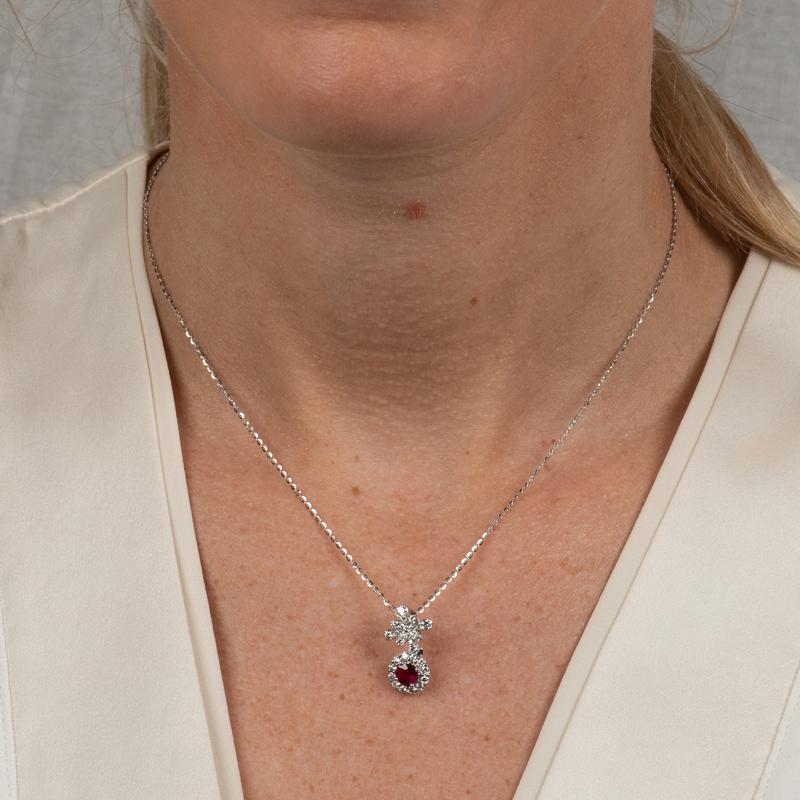 This necklace features a 0.57 carat natural round ruby accented by 0.52 carat in round natural diamonds set in 18 karat white gold. It is set on an 18 karat white gold 16