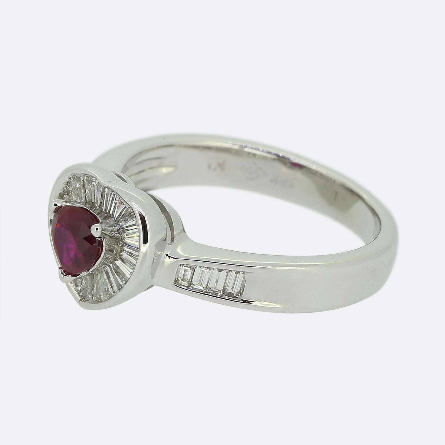 Here we have a delightful 18ct white gold ruby and diamond ring. The centralised ruby is a heart shape, sits slightly risen and possesses a highly desirable intense red hue. Surrounding this principal stone are multiple bright white tapered baguette
