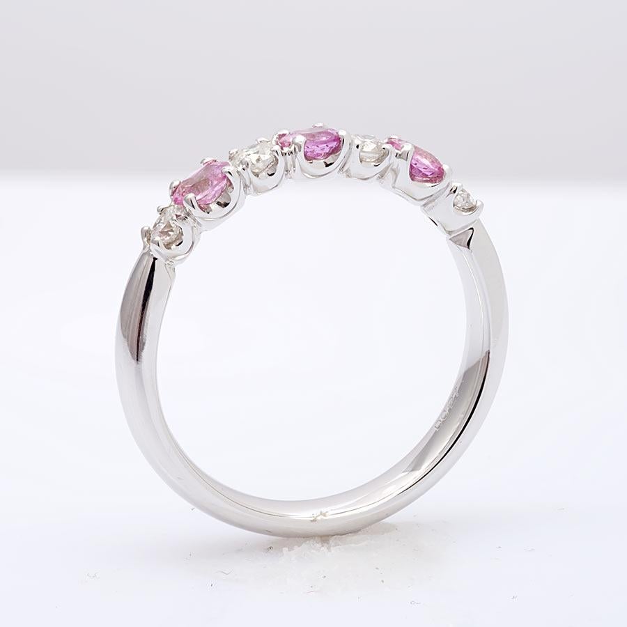 This half studded band has been set with pink sapphires and diamonds in calibrated sizes. 18k white gold holds each gem in a secure prong setting. The light pink tones are currently a trending color like the pastel colors of Rose Quartz. The perfect