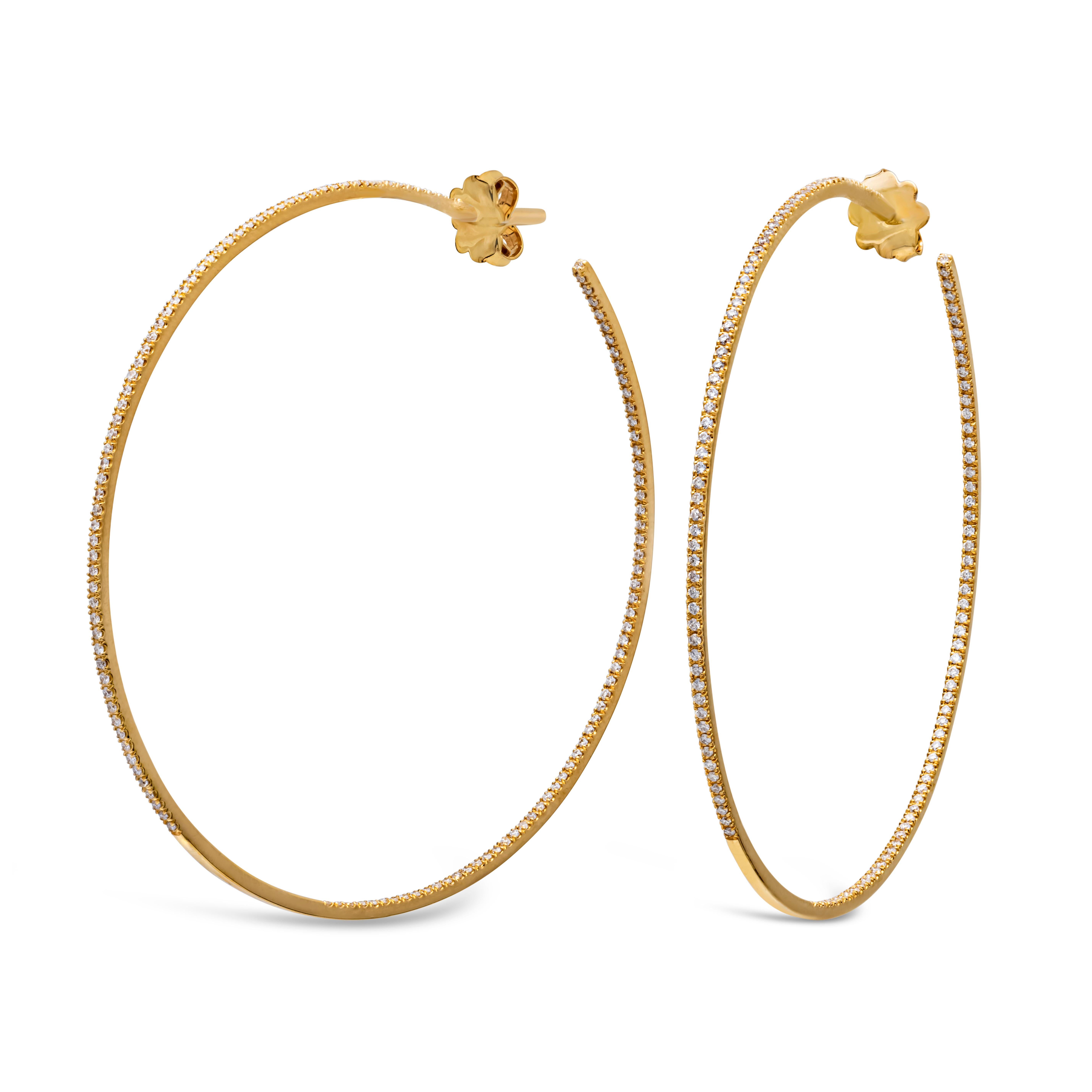 A fashionable and stunning large hoop earrings showcasing a row of 280 round brilliant diamonds, set inside and out in a traditional four prong setting weighing 0.58 carats total, F color and VS-SI1 in clarity. Finely made in 18k yellow gold and