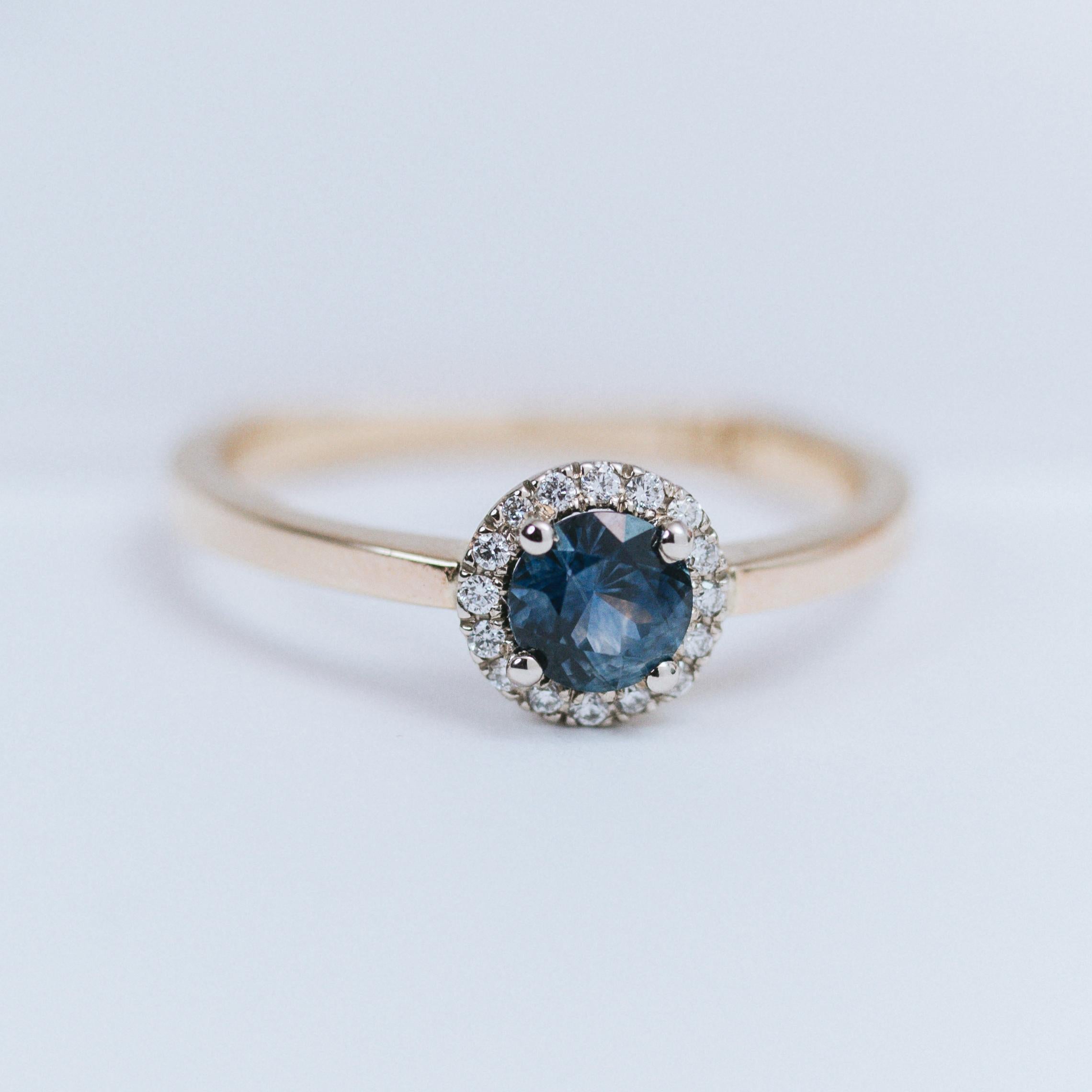 Ring in 14k gold with a 0.5 carat (5mm) Montana sapphire and natural 1mm diamonds halo.
Gemstone setting is made of 14k white gold, the band is made of 14k yellow gold.
Other colors and karats of gold, as well as platinum are available. We can also