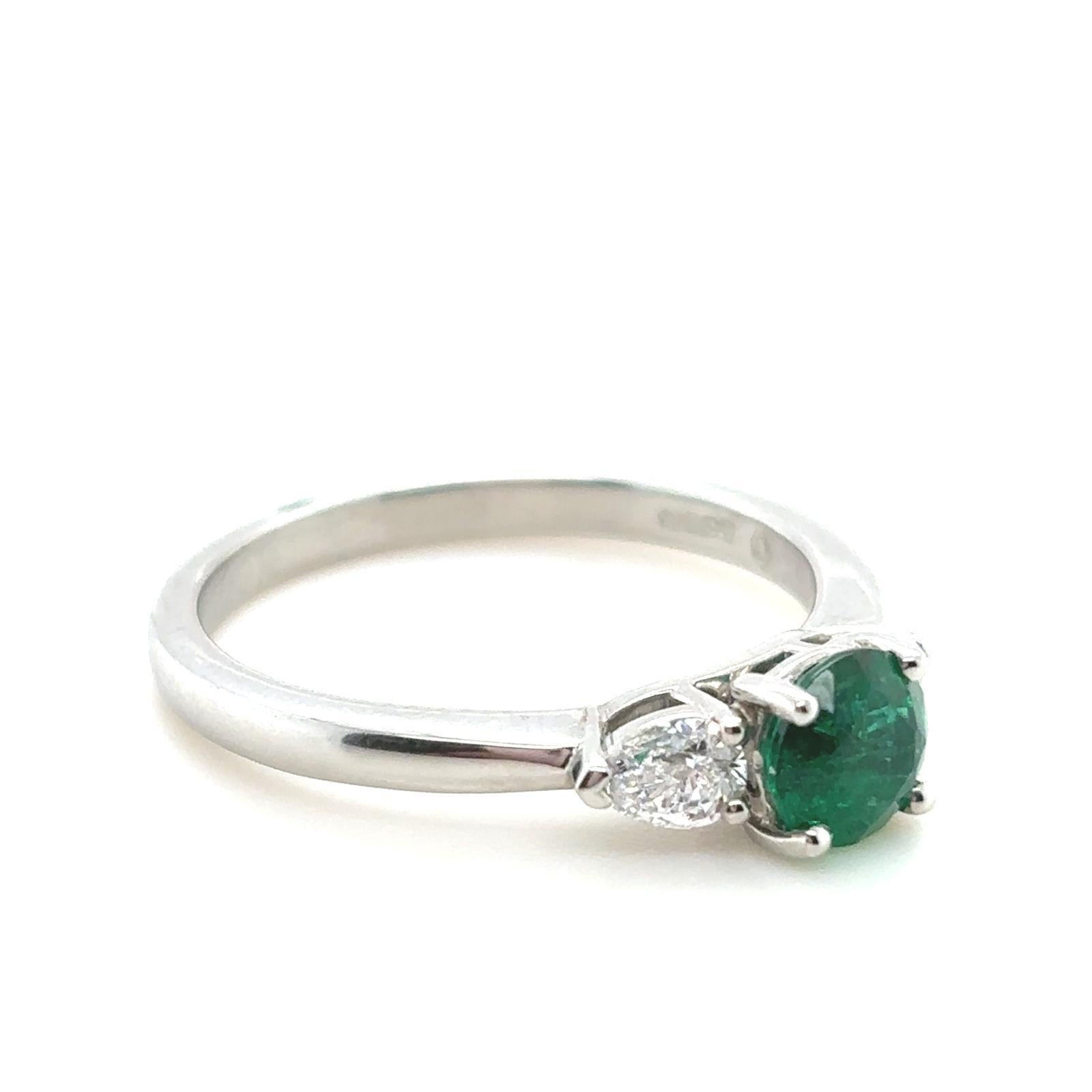 A 0.60 carat emerald and diamond three stone platinum engagement ring.

This beautiful emerald and diamond engagement ring is handcrafted in platinum. The piece is claw set to its centre with an round cut emerald of 0.60 carats. This striking stone