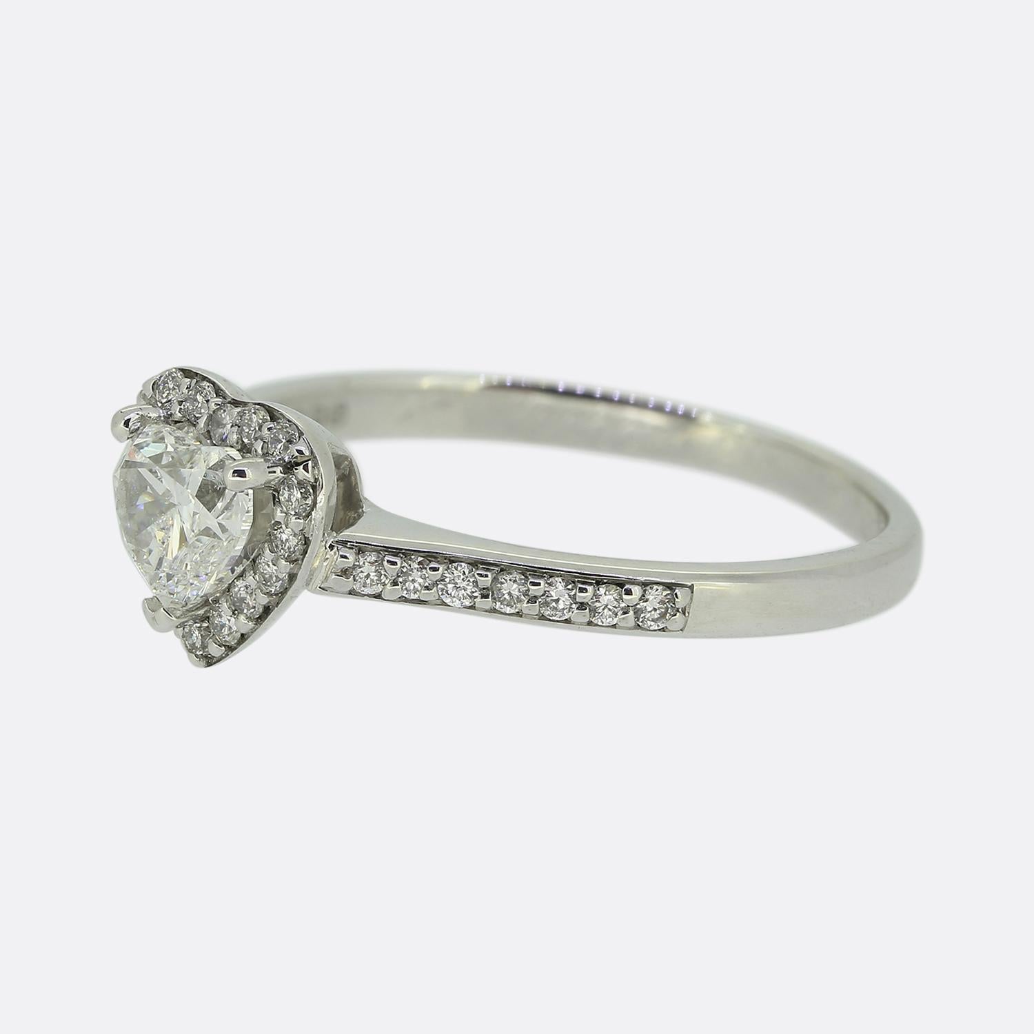 Here we have a delightful diamond cluster ring. This romantic piece showcases a 0.40 carat heart-shaped diamond held in a three-clawed setting at the centre of the face. This bright white principal stone sits slightly risen whilst being surrounded