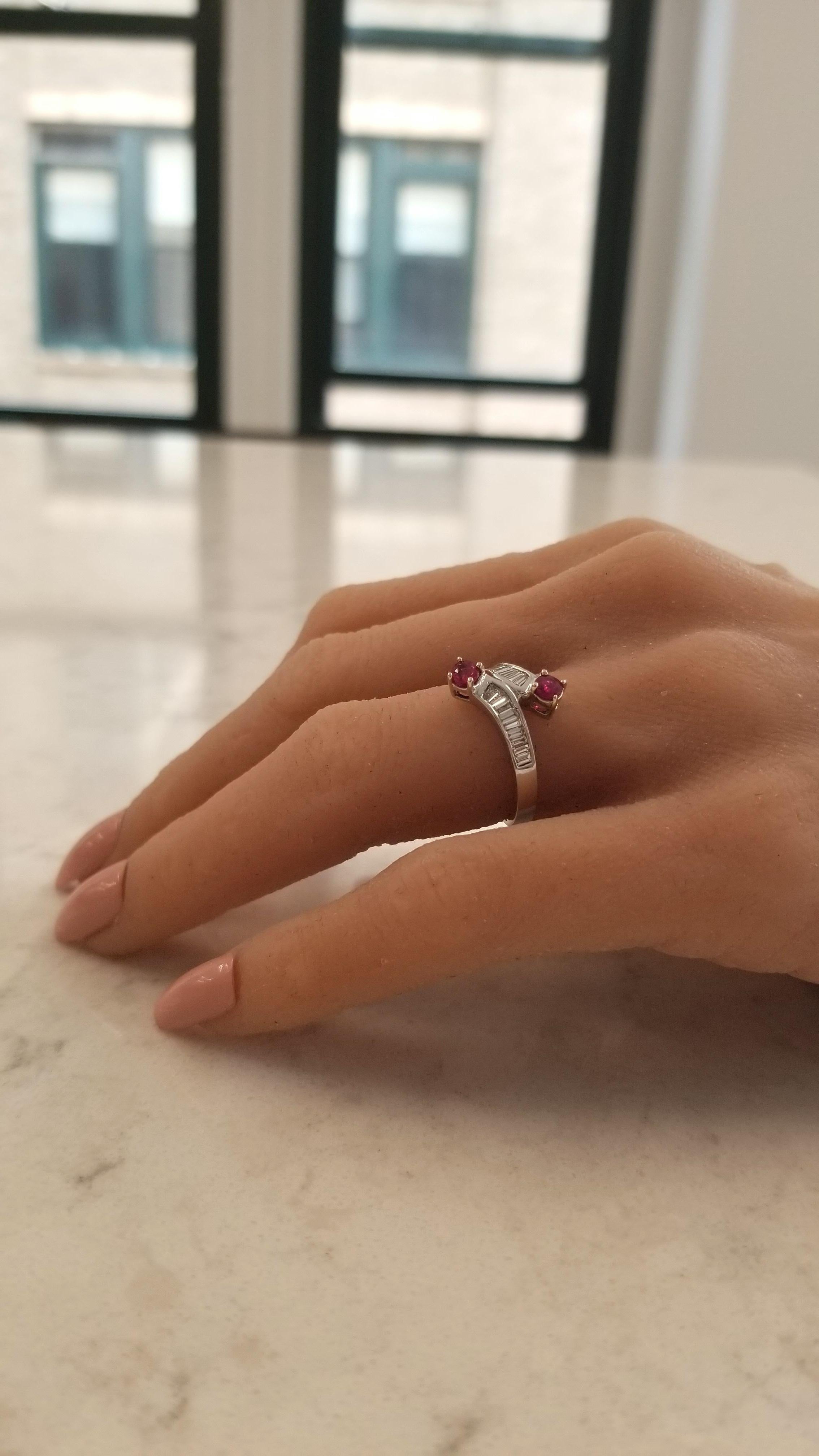 This custom made contemporary bypass fashion anniversary ring is finely crafted in brightly polished 14 karat white gold and features 0.55 carats of rubies that are round cut and yellow gold prong set in a 2-stone setting. Shimmering baguette cut