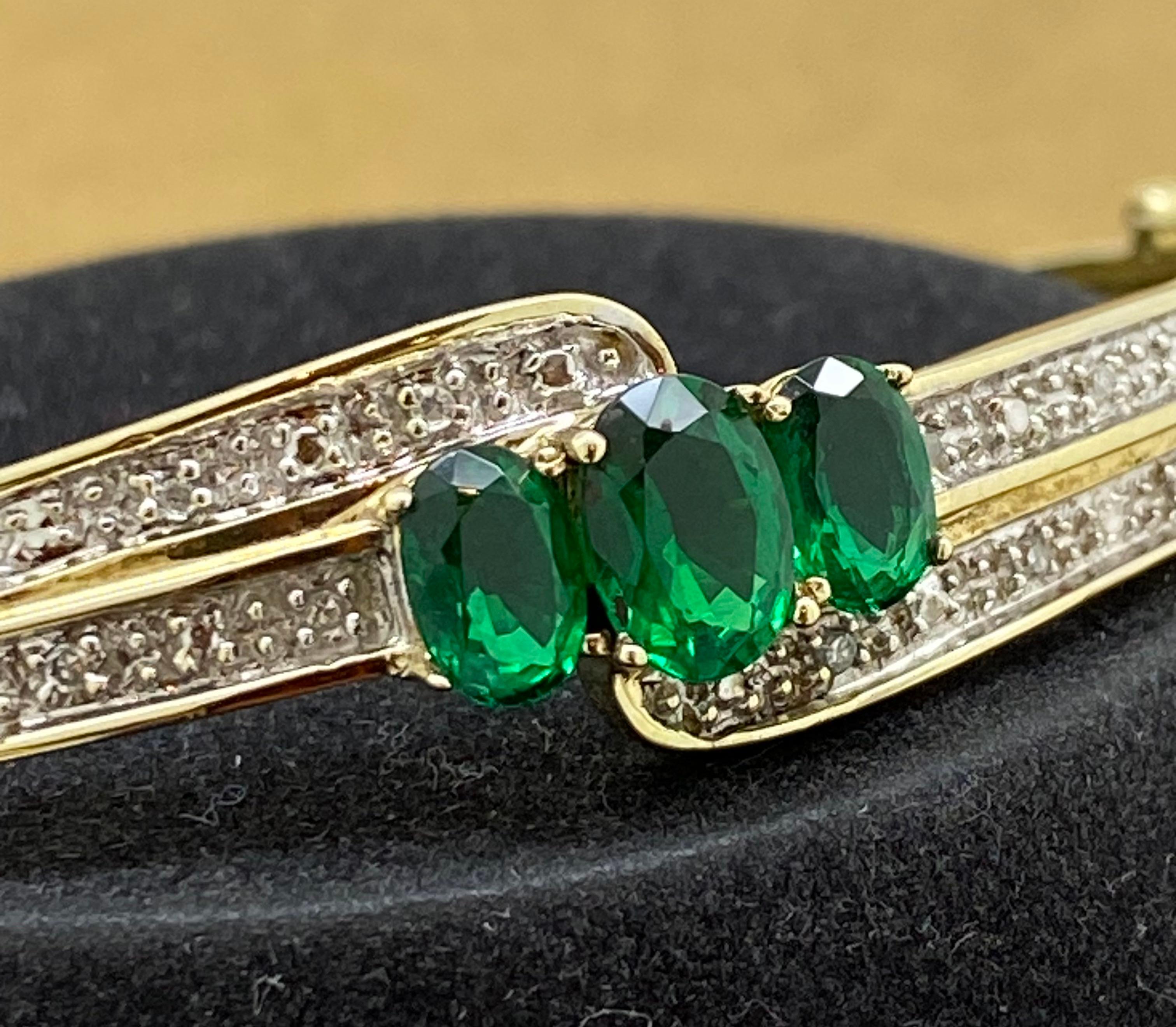 This lovely vintage bangle is centrally set with  
3 Gilson (lab-grown) Emeralds 
of superb vivid grass green colour 
of oval shape, measuring:
1 = 8mm x 5mm 
2 = 6mm x 4.5mm 
totalling 2.00ct approx.

Adorned with natural sparkling round brilliant