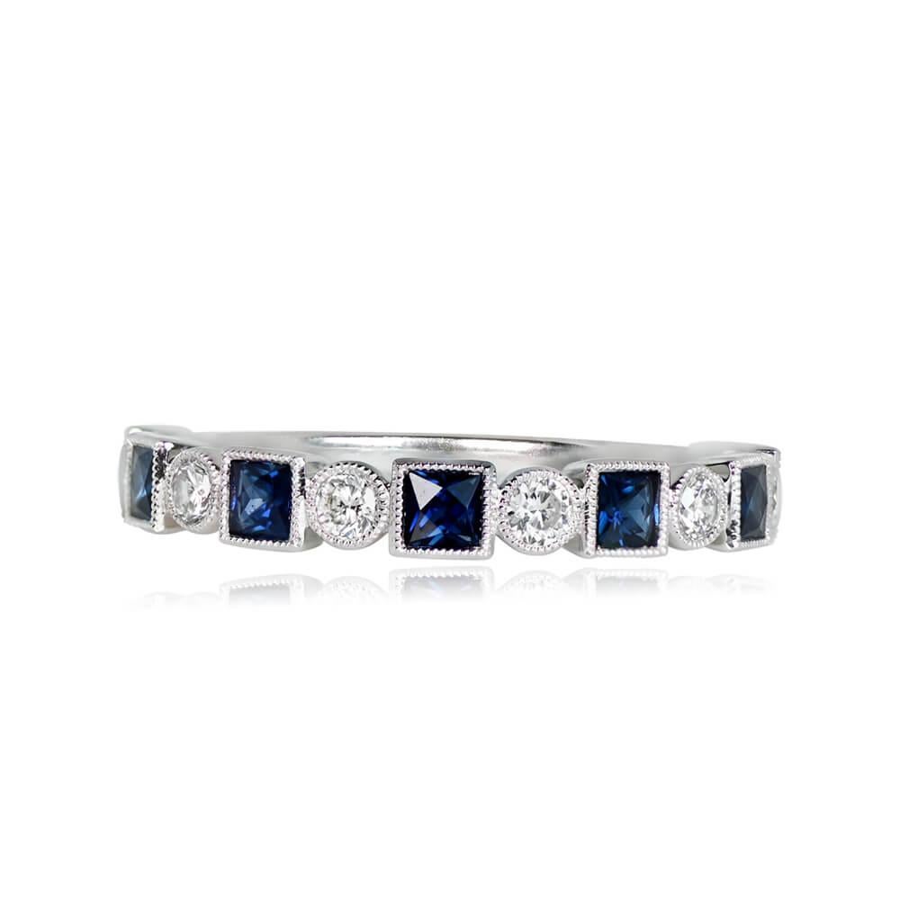 A half-eternity band crafted in platinum, adorned with 0.60 carats of French-cut natural sapphires alternating with 0.23 carats of round brilliant cut diamonds. The stones are set in bezels embellished with fine milgrain, and the band has a width of