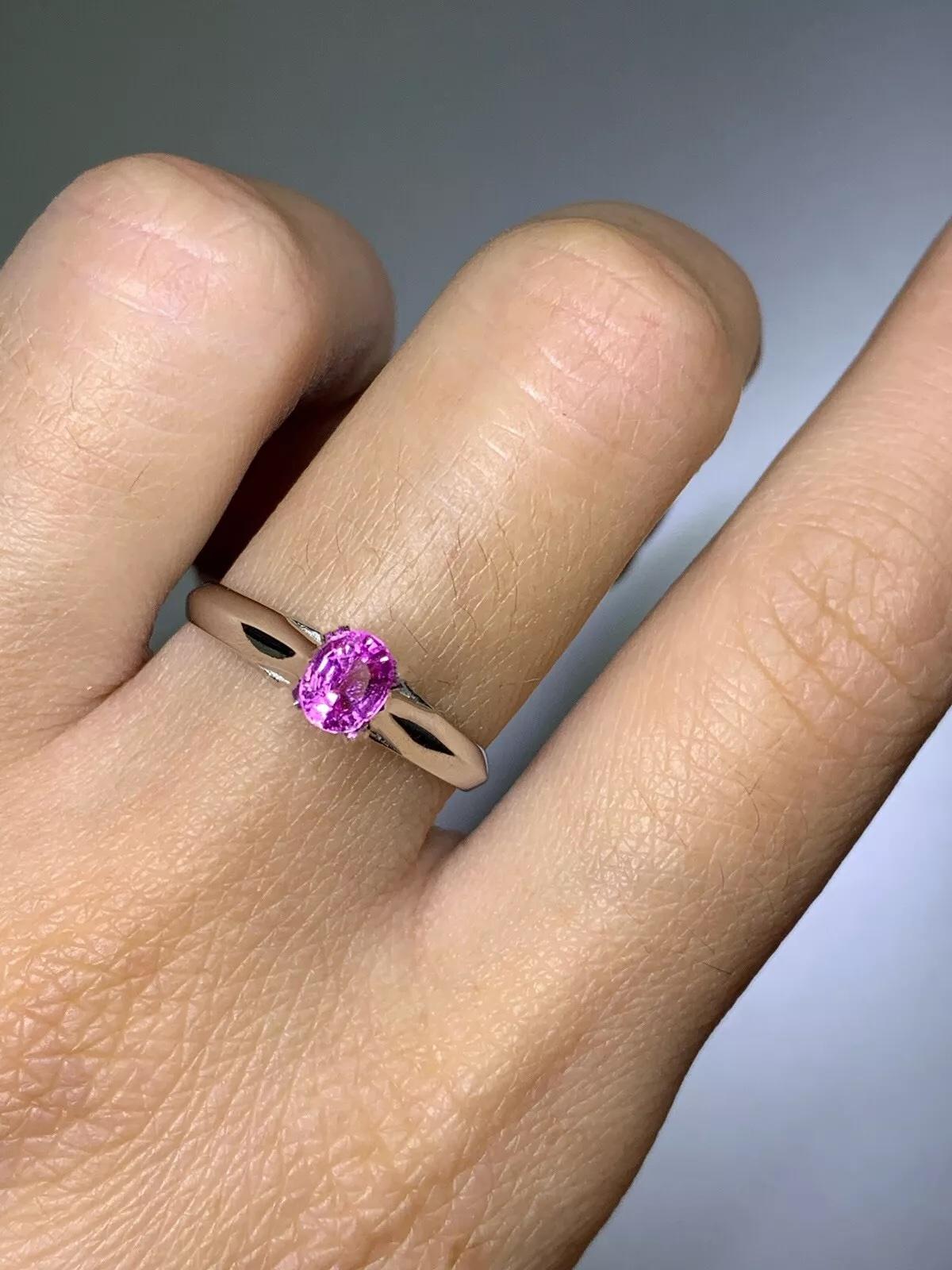 Cette magnifique bague de fiançailles en saphir présente un saphir rose de forme ovale parfaite, serti dans de l'or blanc 18ct. La pierre précieuse est naturelle et n'a pas été améliorée, et elle brille avec une excellente qualité de taille. Le