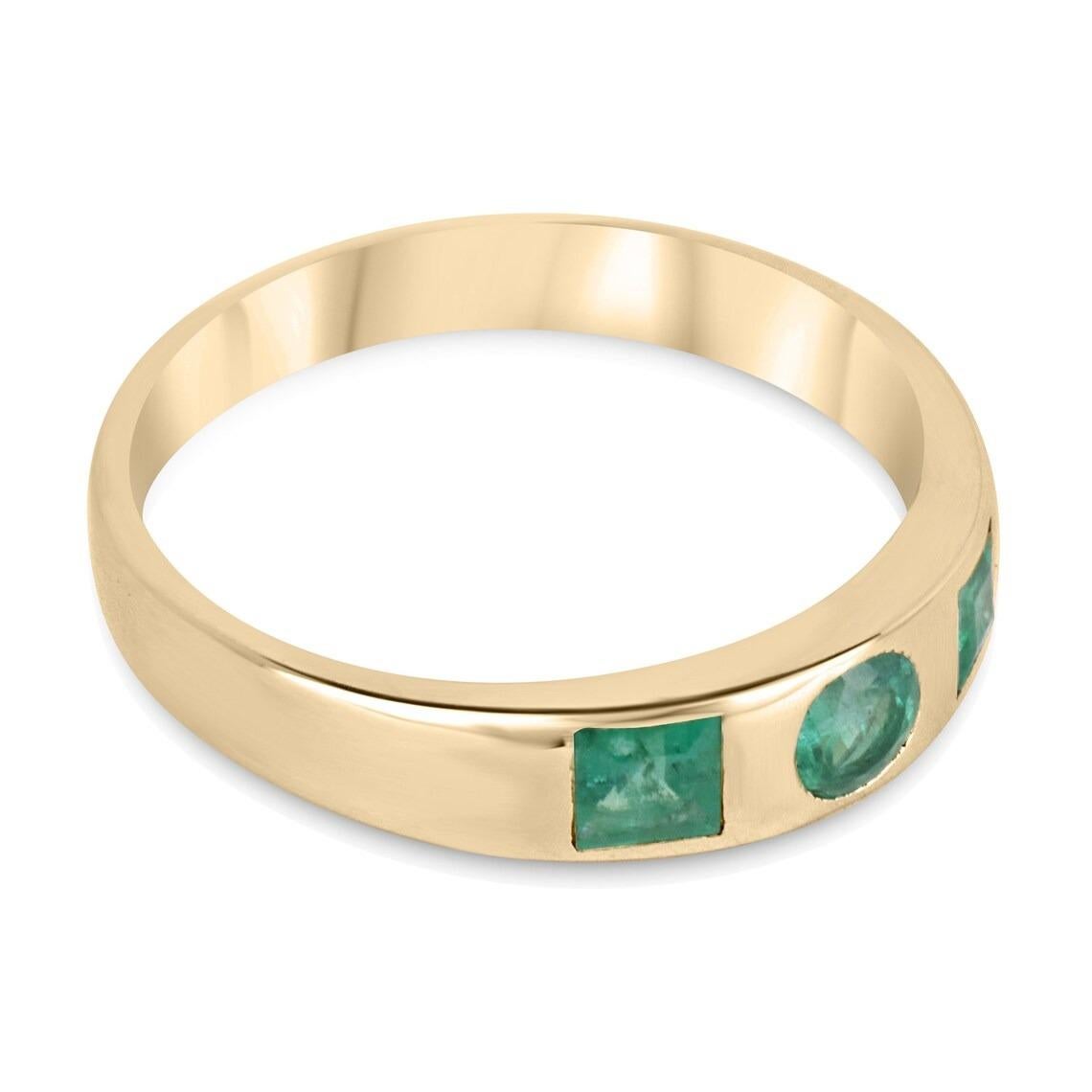 A stunning emerald three-stone ring that features a round cut emerald in the very center, with two princess cut emeralds accenting either side. The total combined weight for this piece is 0.60-carats, displaying a lush green color and good luster.
