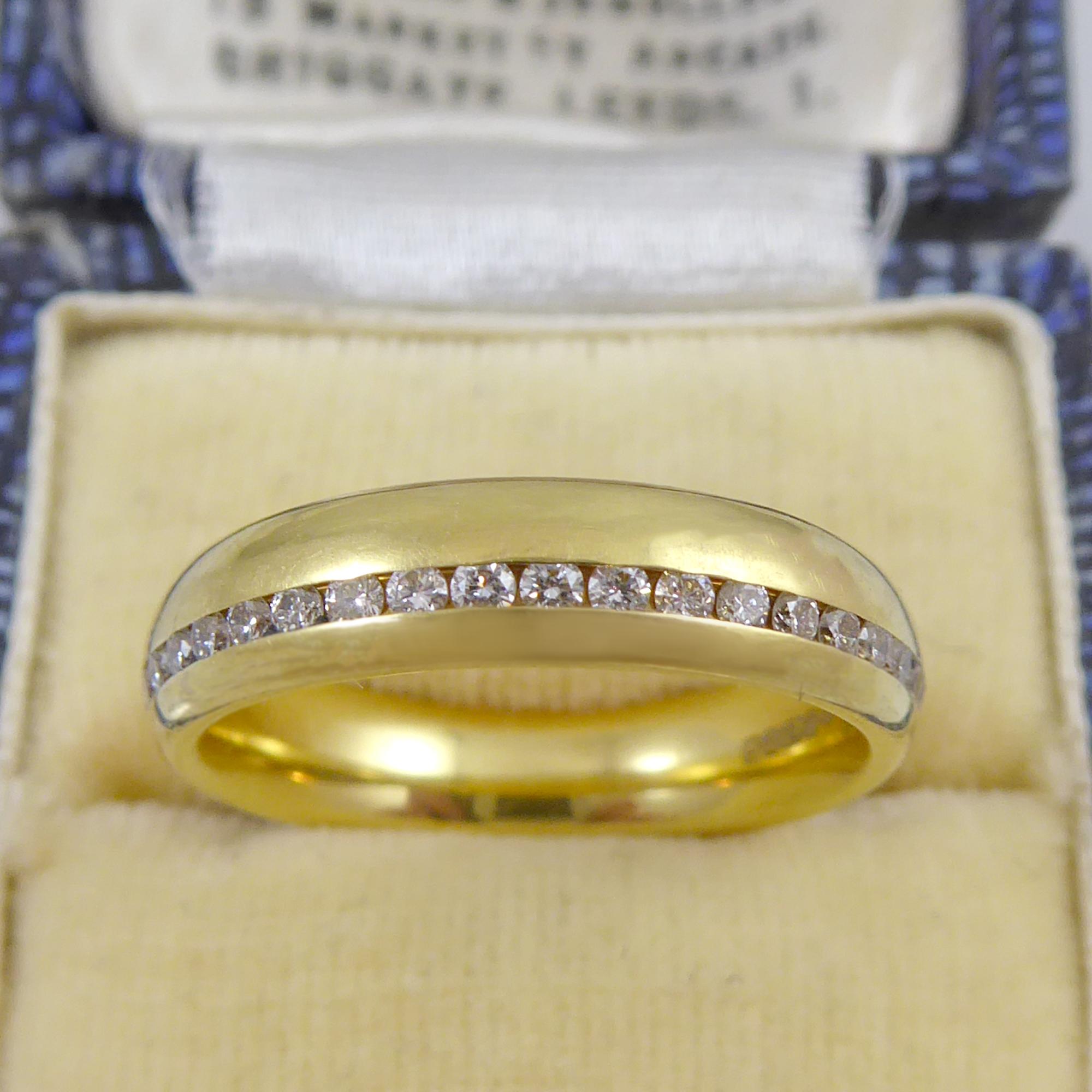 A pre-owned, D shaped cross-sectioned 18ct yellow gold band set with 0.61ct of brilliant cut diamonds channel set to one edge of the band.  Finger size 6.75 (US/Canada), N1.2 (UK/Australia), no resizing is possible.  Measuring 4.8mm wide.