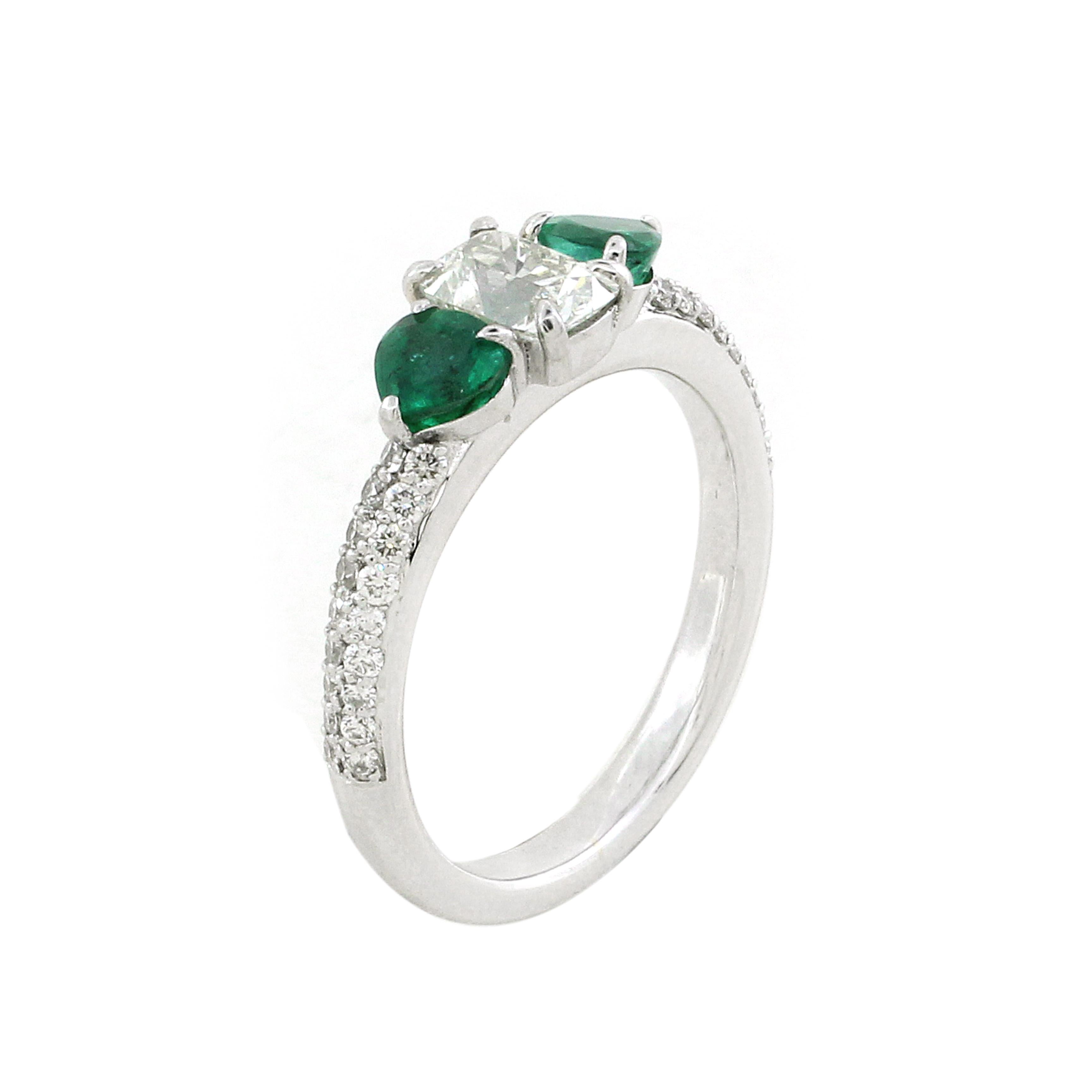 Dieser elegante Dreisteinring besticht durch einen 0,62-karätigen Diamanten im Fancy-Oval-Schliff in der Mitte, flankiert von zwei auffälligen birnenförmigen Smaragden von insgesamt 0,62 Karat. Der zentrale Diamant mit seinem exquisiten Schliff und