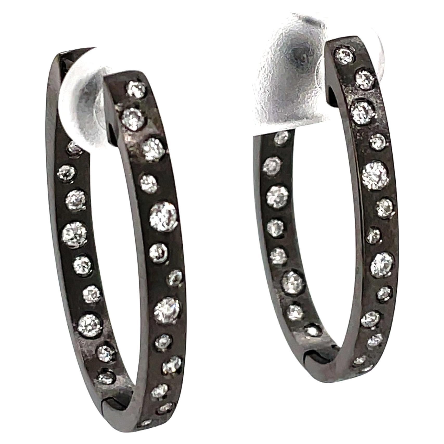These Diamond earrings are a stunning and timeless accessory that can add a touch of glamour and sophistication to any outfit. These Flush Set Oval Hoop Earrings contain 0.63 Carats of Round White Diamonds , set in 14K Black Gold (Black Rhodium on
