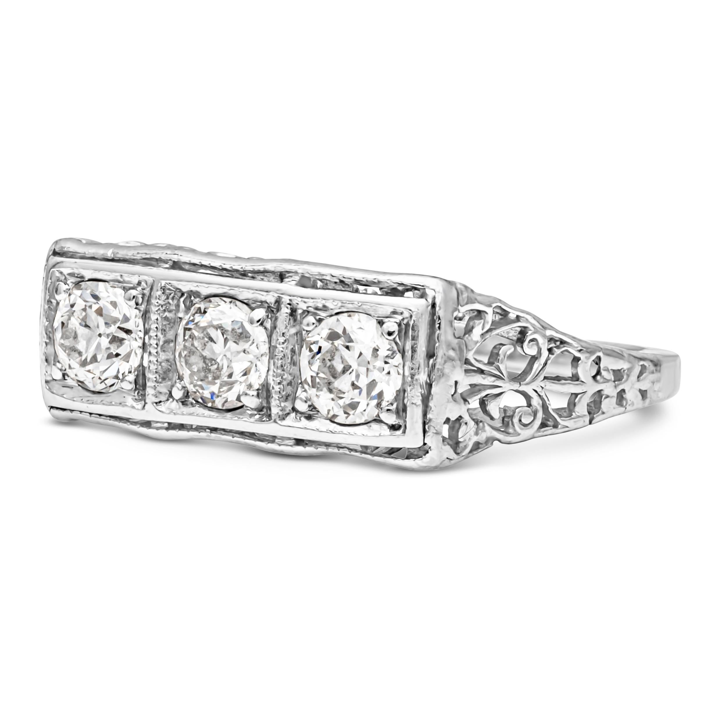 A lustrous antique-style wedding band, showcasing three old European cut diamonds weighing 0.63 carats total with G color and VS clarity, set on a classic four prong basket setting and an intricately-designed polished platinum mounting. Size 5.75