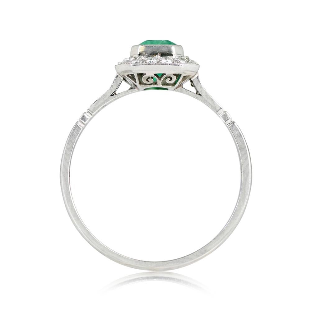 Emerald Halo Ring: A dainty masterpiece highlighting a bezel-set, natural emerald cut emerald, weighing around 0.63 carats. Embracing the center gem, a halo of round brilliant cut diamonds sparkles. Adorning each shoulder are three more round