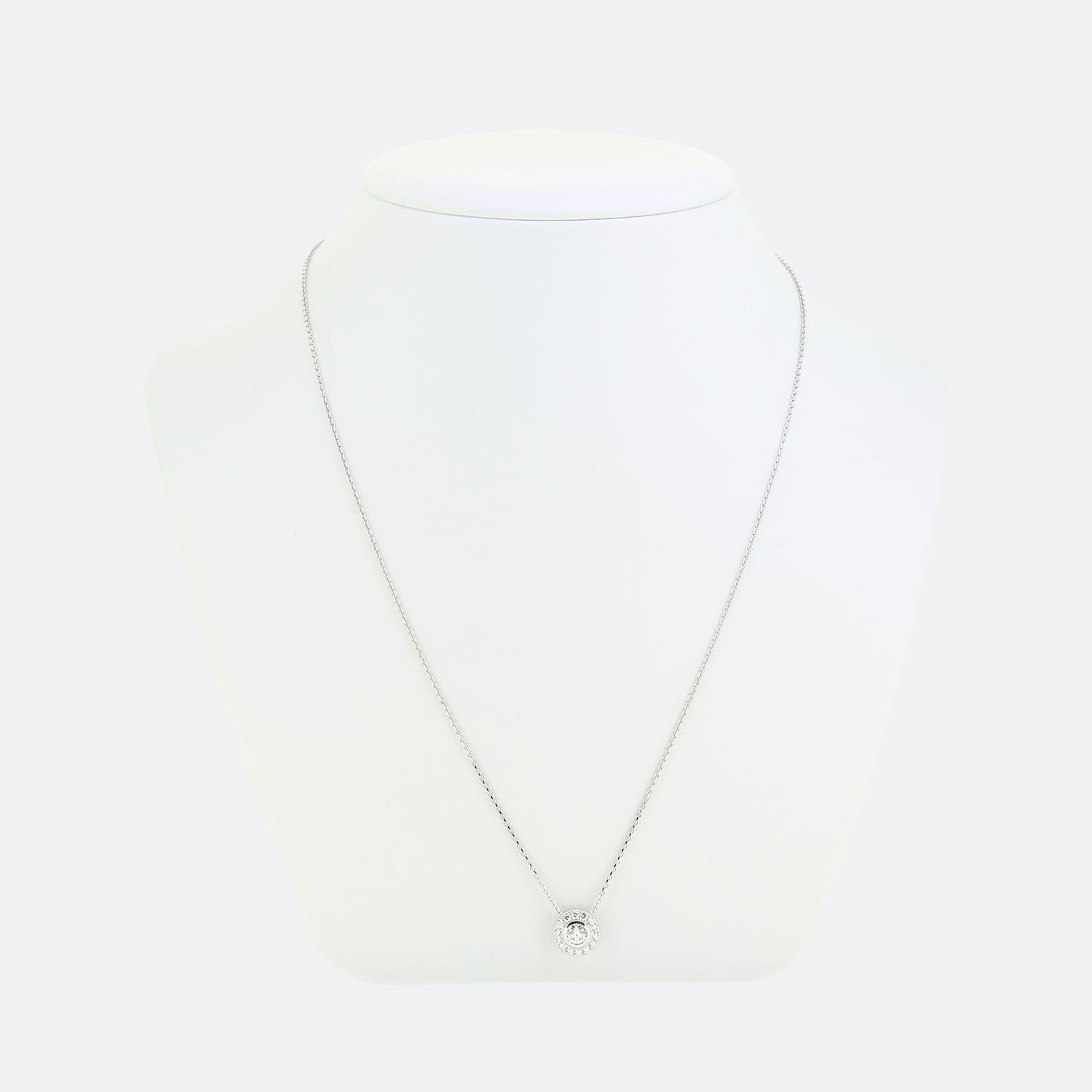 This is an 18ct white gold diamond halo pendant. The pendant features a focal centralised round brilliant cut diamond which has been rub-over, surrounded by an array of matching claw set natural diamonds in a halo setting and suspended from a 9ct