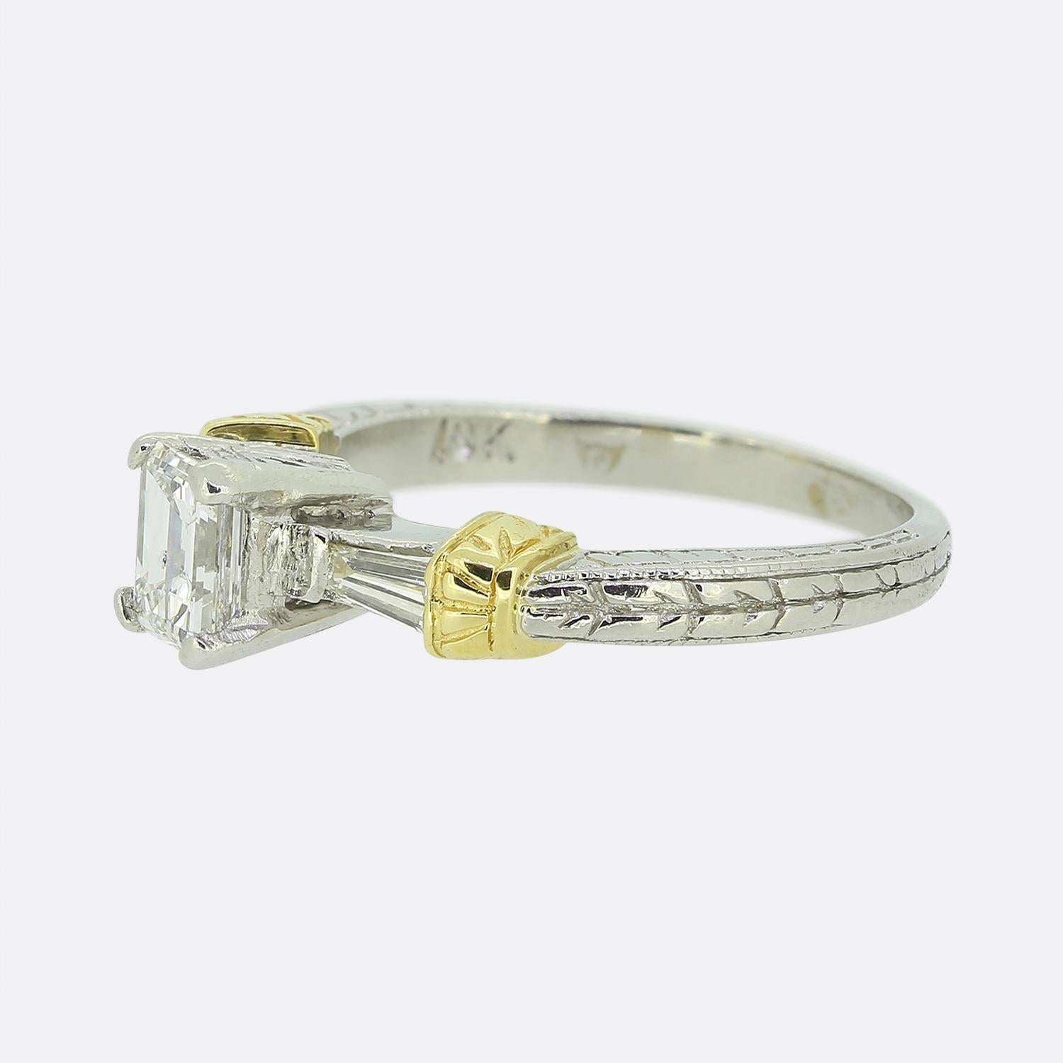 Here we have a platinum and 18ct yellow gold diamond engagement ring. The focal point of this ring is a single emerald cut diamond which sits slightly risen at the centre of the face with a tapered baguette cut diamond on each shoulder.

Condition: