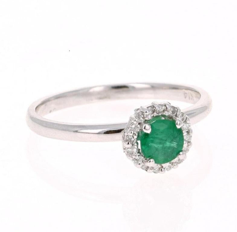 This is a cute and dainty Emerald and Diamond Ring! 

This 14K White Gold Ring has a Round Cut Emerald that weighs 0.54 carats and is surrounded by a Halo of 16 Round Cut Diamonds that weigh 0.10 carat (Clarity: SI2, Color: F). The total carat