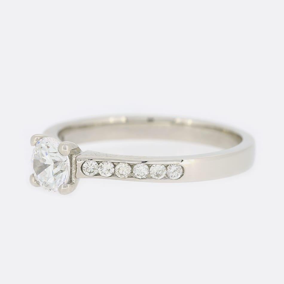 Dies ist ein Single Stone Diamant-Verlobungsring. Im Mittelpunkt dieses Rings steht ein runder Diamant im Brillantschliff, der in einer vierfachen Krappenfassung aus Platin mit kanalgefassten Diamantschultern gefasst ist.

Zustand: Gebraucht (Sehr