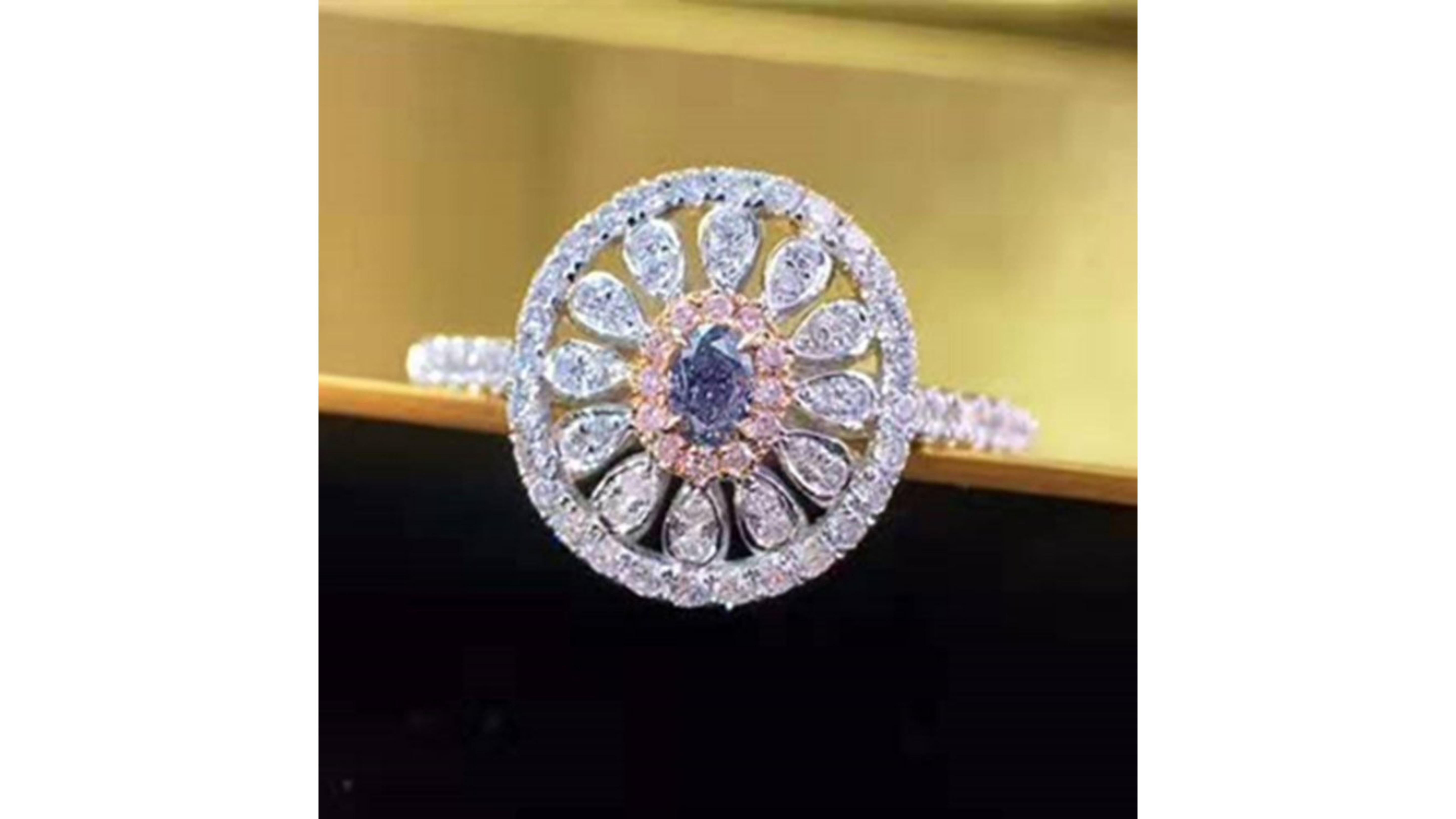 Fancy Blue And Pink Diamond Ring with 51 diamonds  set in 18 Karat White Gold .    This is a Blue Diamond  with small Pink Diamonds around it and also White ones too.   A lot of these came from the Argyle mine in Australia which has closed down so