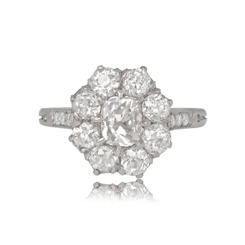 An exquisite cluster engagement ring boasts an elongated antique cushion-cut center diamond, weighing around 0.65 carats. The center diamond is embraced by a cluster of old European cut diamonds. Hand-crafted in platinum, this ring maintains a low