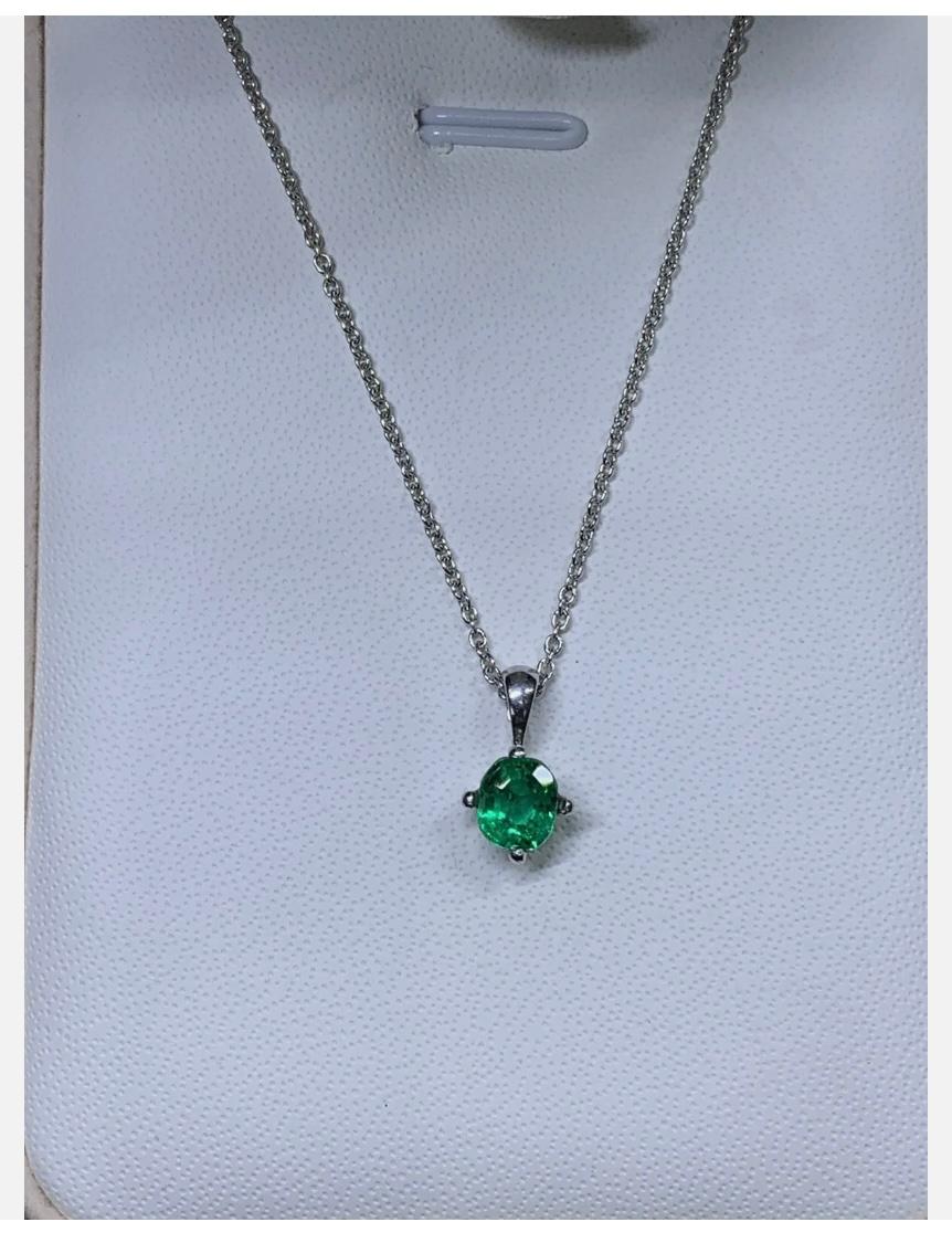 Collier à pendentif solitaire en or blanc 18ct avec émeraude colombienne de 0,65ct
Ce magnifique collier pendentif est orné d'une superbe émeraude colombienne de 0,65ct, sertie dans un solitaire classique. Le pendentif rond est en or blanc 18ct et
