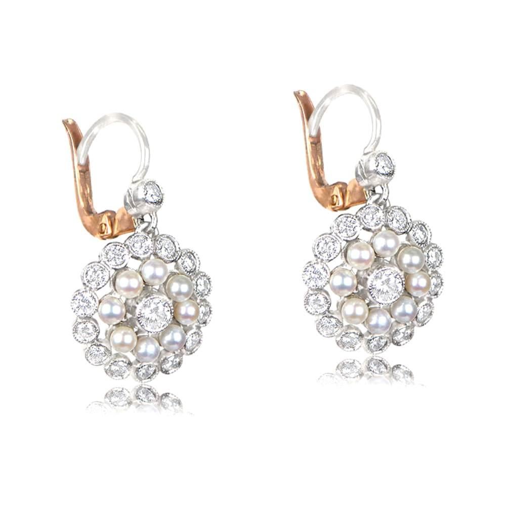 Behold these captivating Edwardian-style pearl and diamond earrings, a true embodiment of vintage glamour. Crafted in platinum, these earrings feature center stones weighing 0.08 carats each, beautifully accentuated by a mesmerizing double halo of