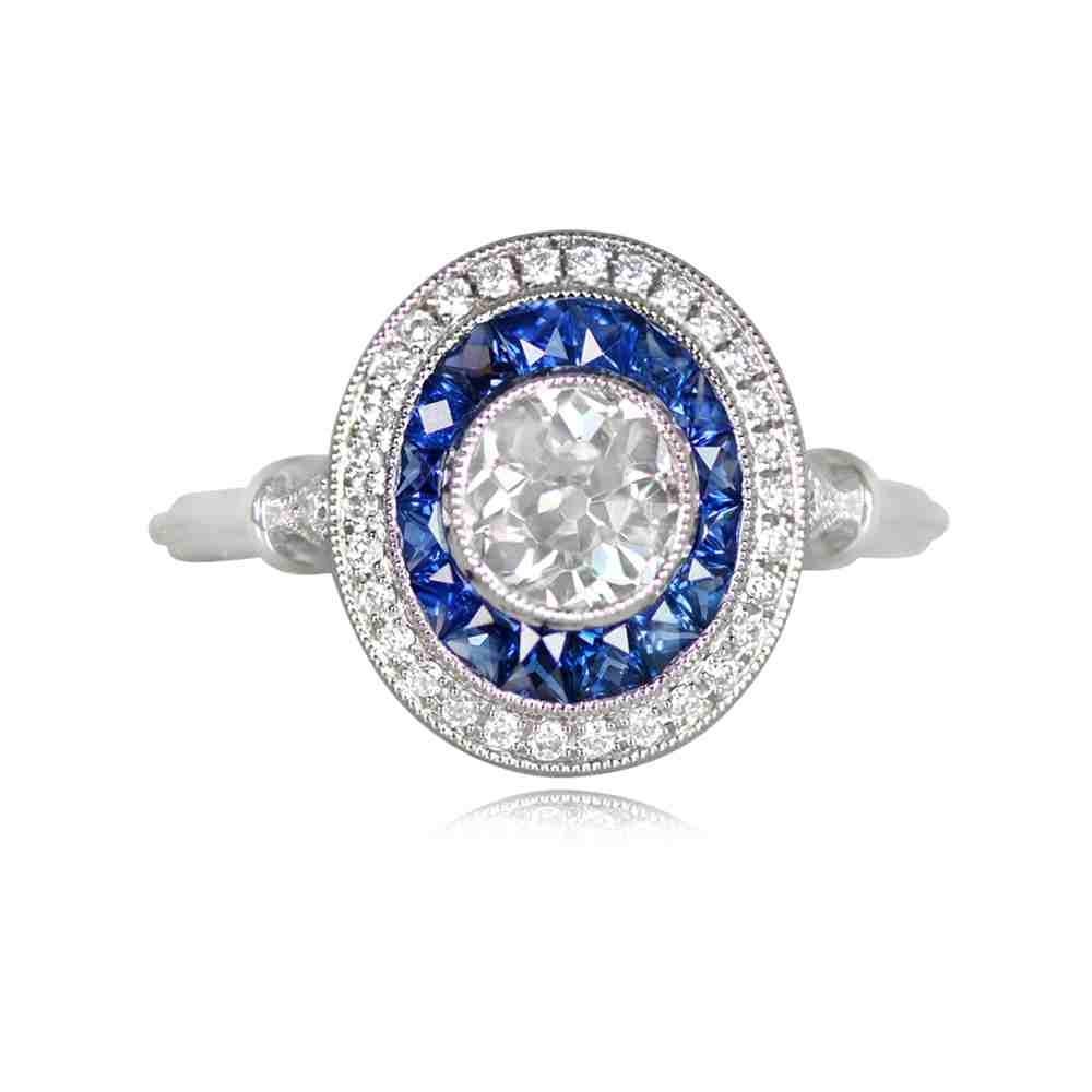 A stunning platinum engagement ring with a bezel-set old European cut diamond, approximately 0.66 carats, K color, and VS clarity. The center diamond is encircled by a double halo. The inner halo is composed of natural French-cut blue sapphires,