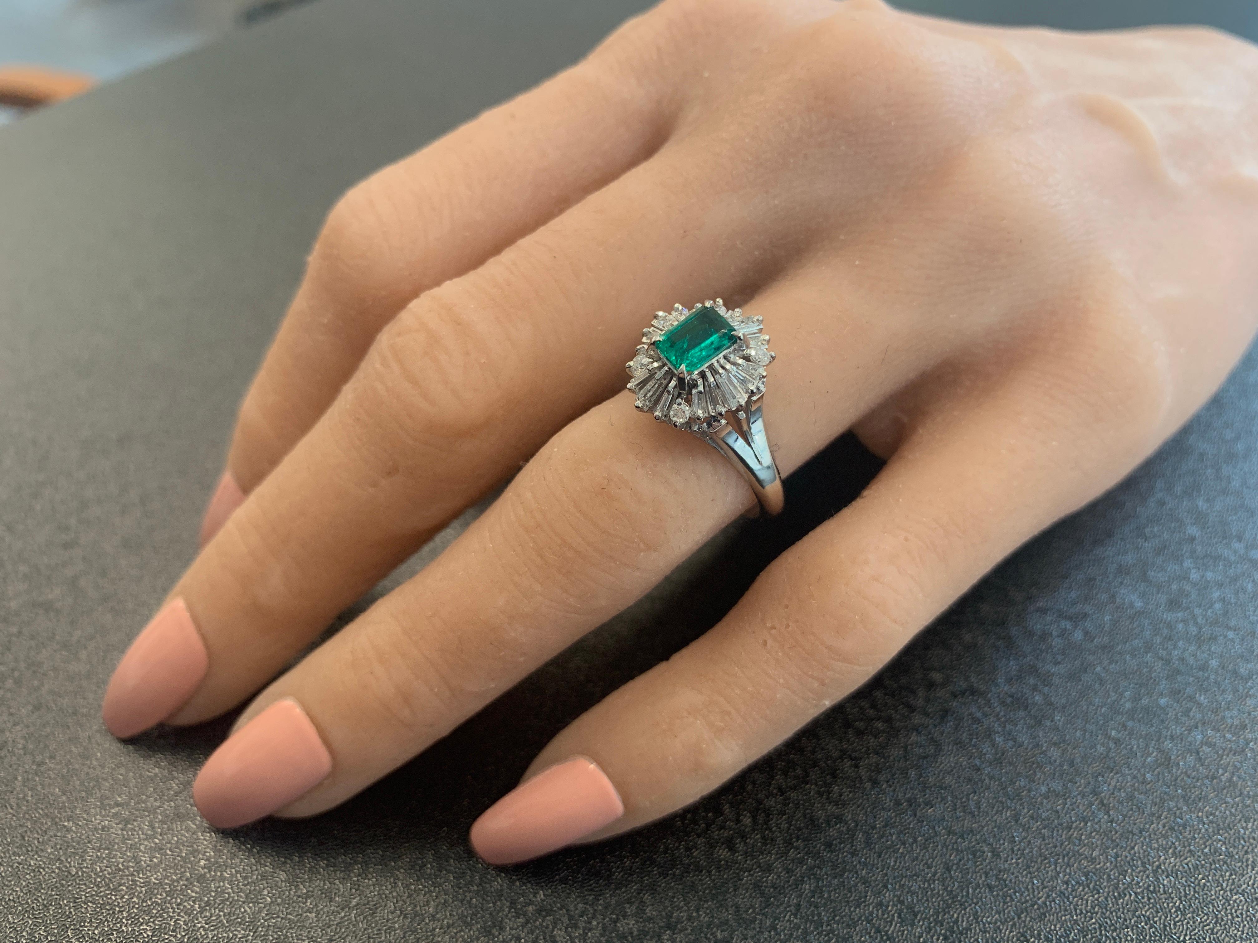 An emerald cut 0.67 carat fine quality emerald sits in the center of this brightly polished platinum ring, creating a luxurious ambiance of style and remarkable sophistication. The gem source is Colombia. The luscious color of this emerald is