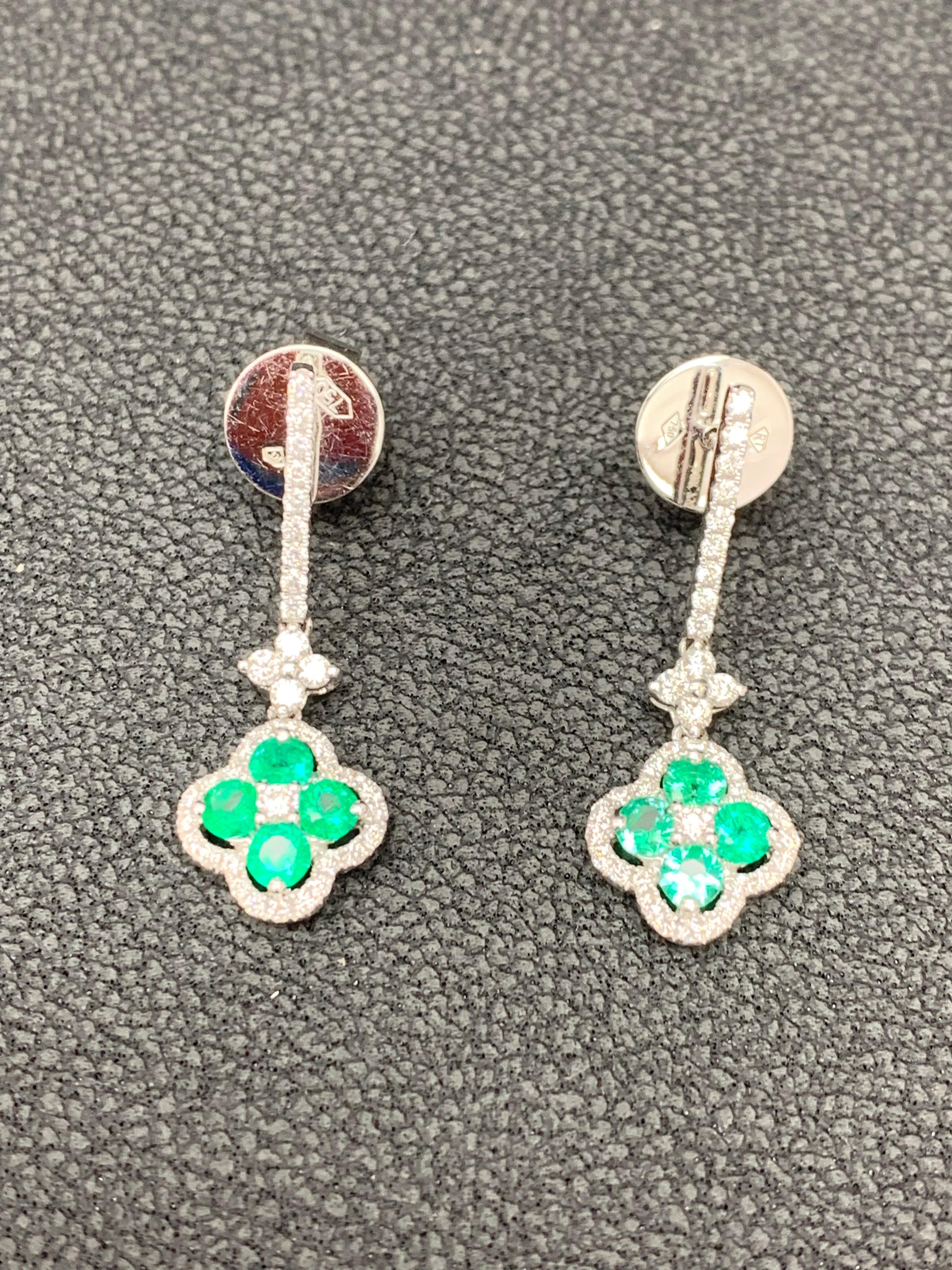A unique pair of earrings featuring open work floral design. Lush green round emeralds weigh 0.68 carats in total which are  surrounded by brilliant-cut diamonds weighing 0.56 carats.