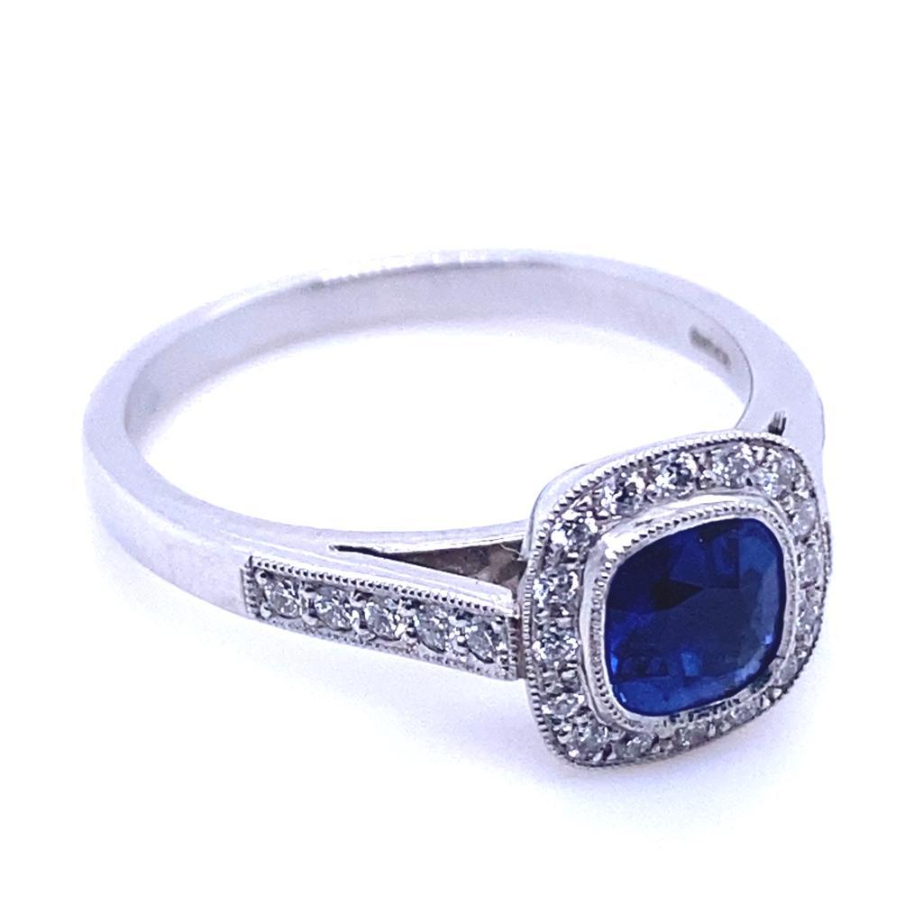 A 0.68 carat sapphire and diamond platinum cluster engagement ring.

This contemporary and classic cluster ring is set with a deep blue sapphire cushion cut centre and round brilliant cut diamond surrounds leading to further half diamond set