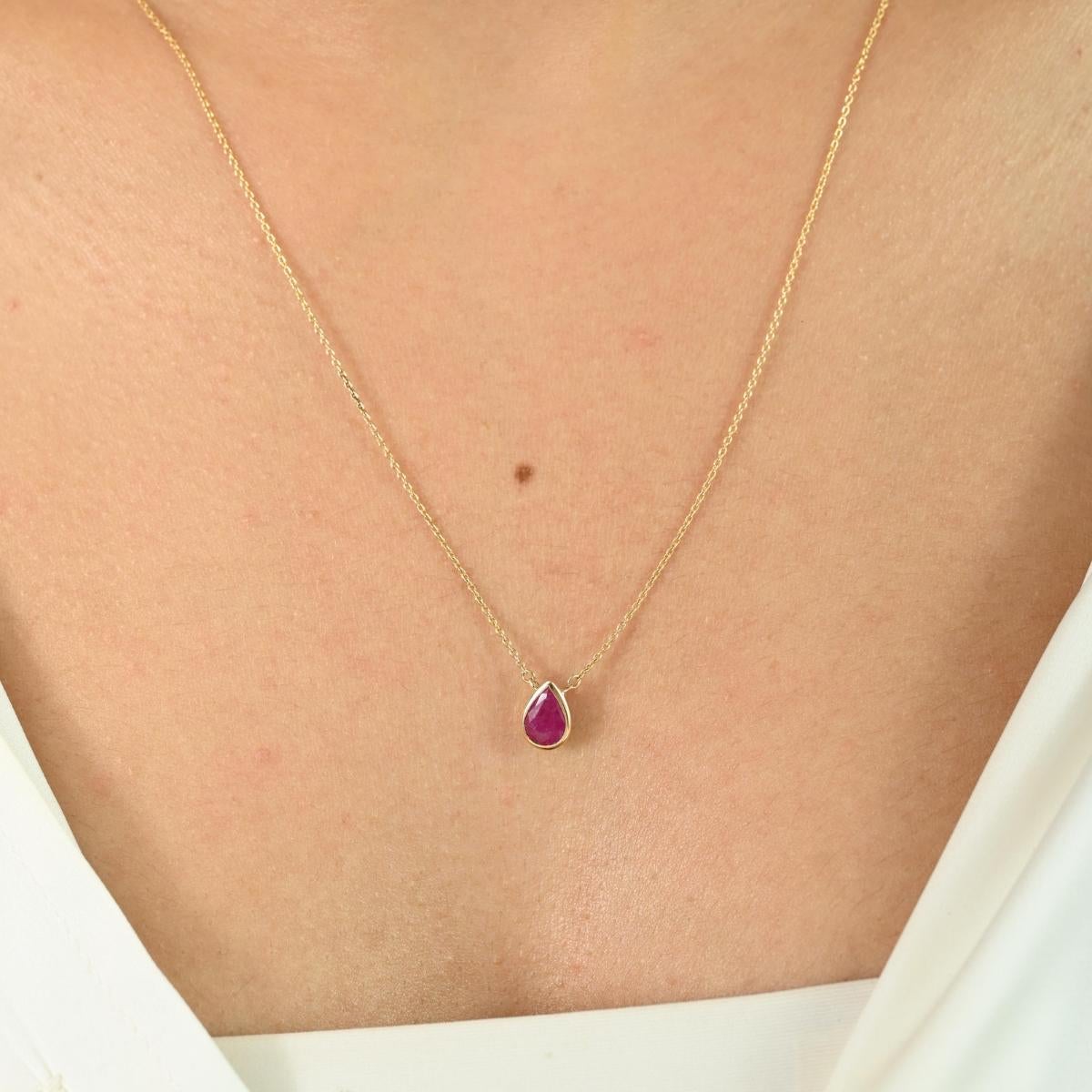 Délicat mais saisissant, cet élégant collier présente une captivante pierre précieuse en forme de poire sertie dans de l'or jaune 14k radieux. La pierre rouge vibrante, d'un poids de 0,68 carat, est magnifiquement encadrée dans une monture biseautée