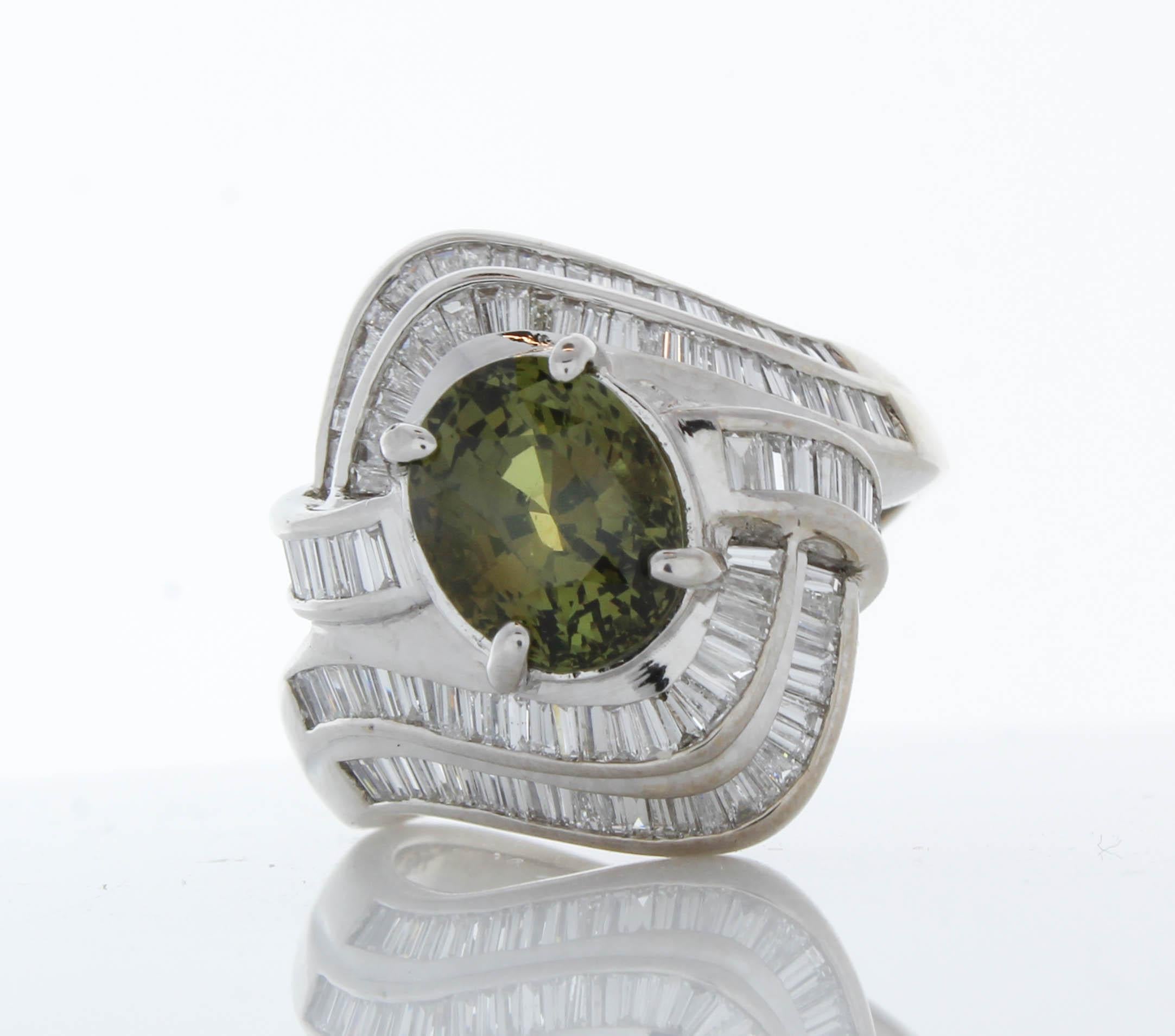 This ring delights the eye with a bold pop of green color. It features a richly saturated 0.69 carat green Emerald. This gem is accented by 2.20 carat total weight of Tapered baguette cut diamonds. The ring is crafted of  18K White Gold to last a