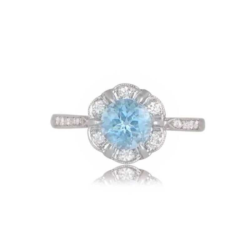 A captivating floral-style platinum ring featuring a vibrant round aquamarine weighing around 0.70 carats at its center. The mesmerizing aquamarine is surrounded by a cluster of exquisite old European cut diamonds, creating a stunning contrast.